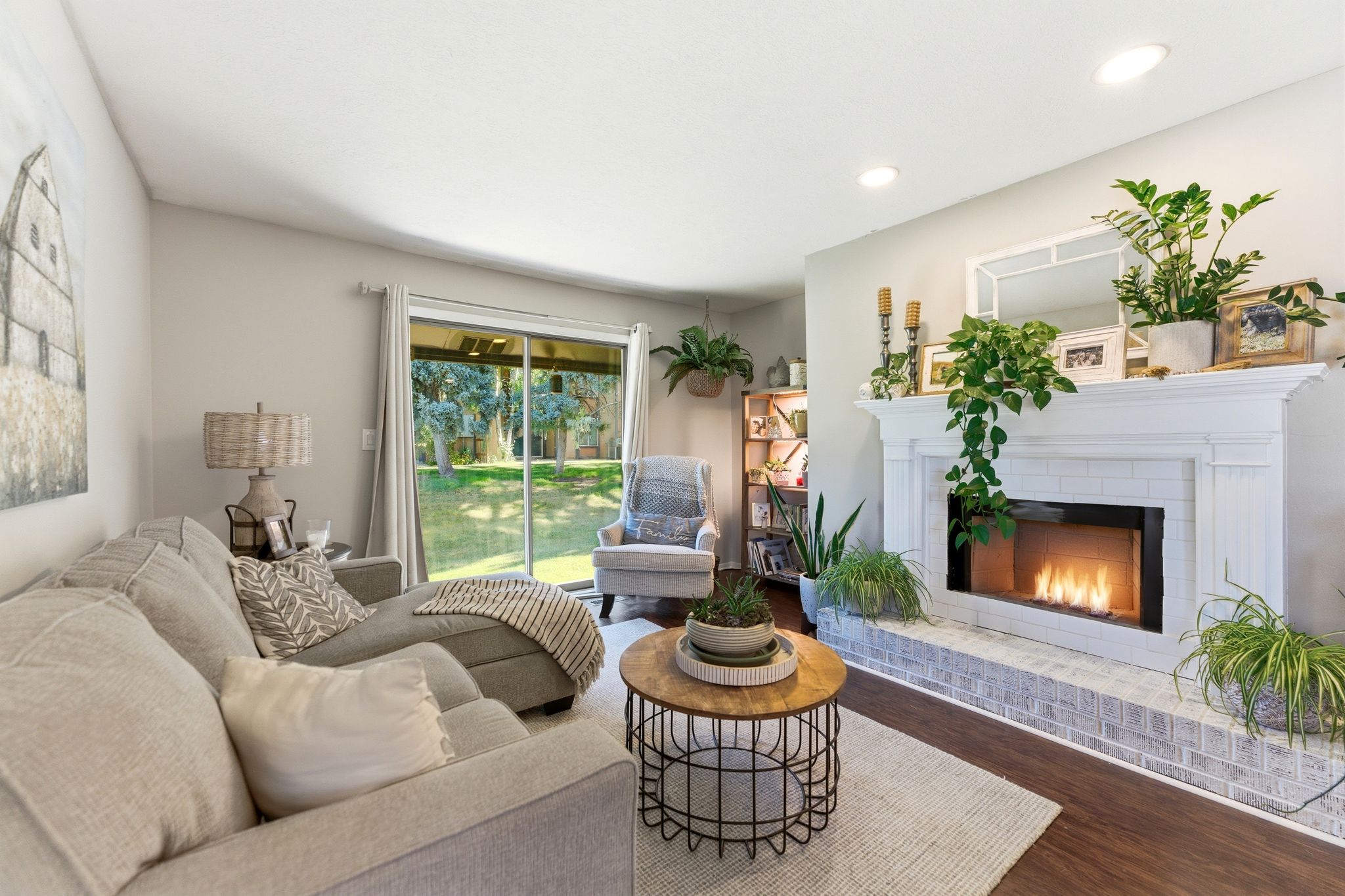 Living room featuring a fireplace with a white mantel and tile surround, wood-finish flooring, recessed lighting, and sliding glass doors opening to outdoor space