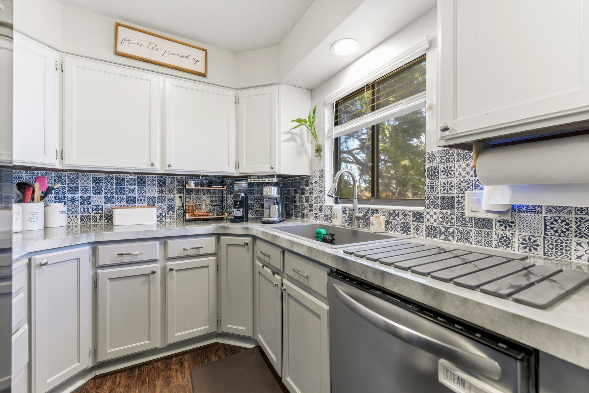 Corner kitchen featuring white upper cabinetry, light gray lower cabinetry, and a mosaic tile backsplash