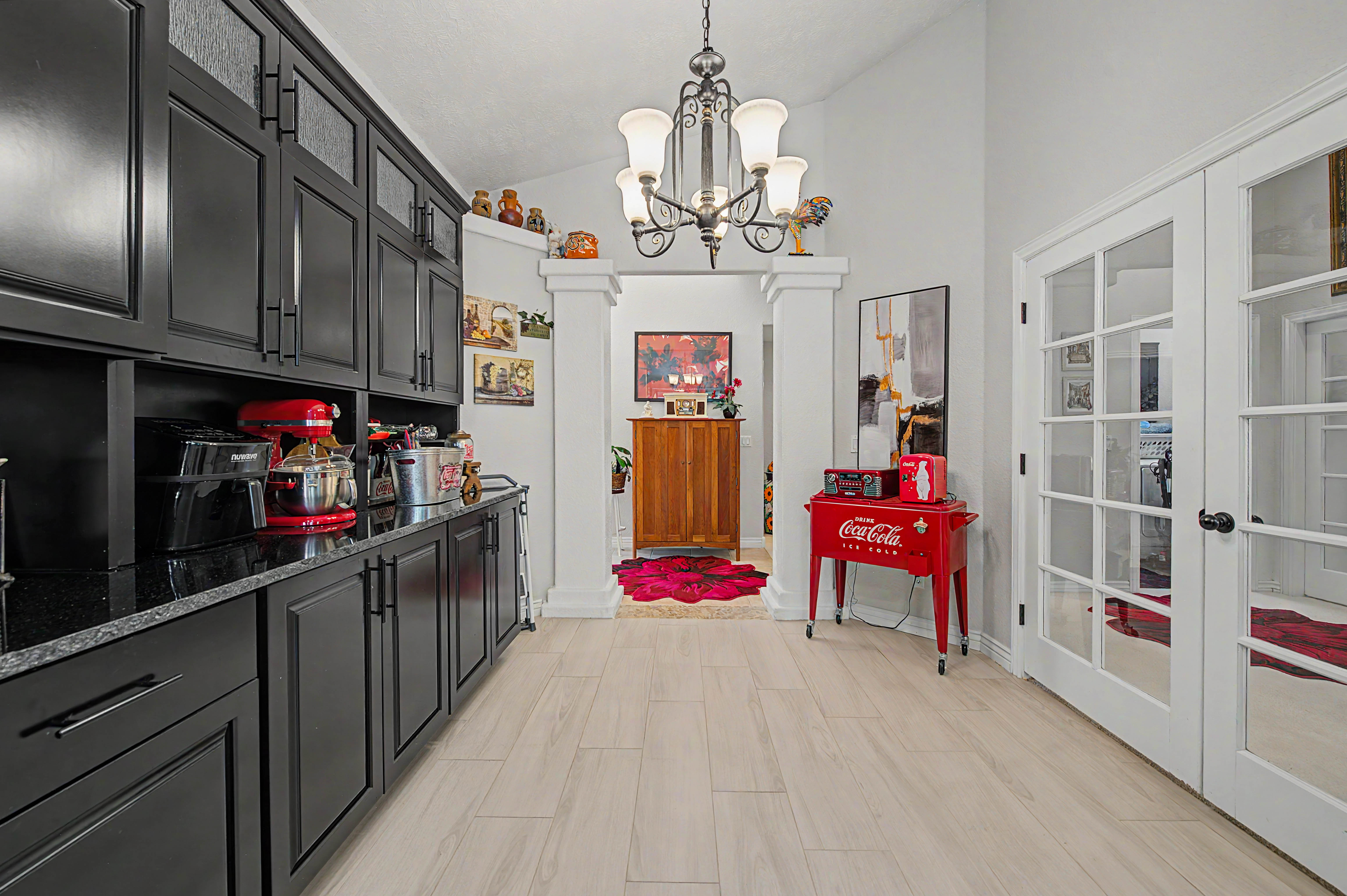 Spacious hallway featuring light-colored wood-finish tile flooring, white walls, and a chandelier light fixture