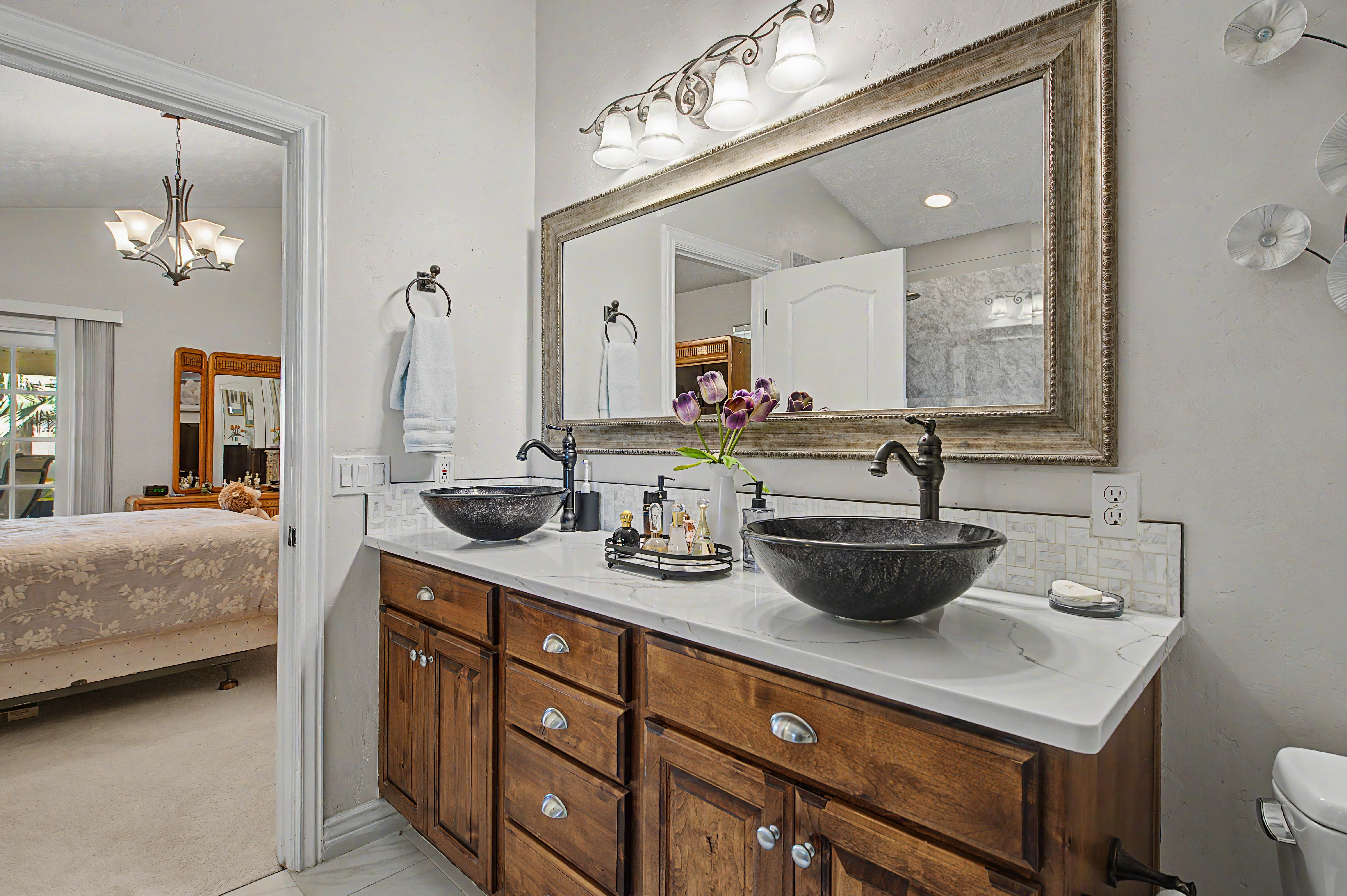Double vanity featuring wood cabinetry, vessel sinks, and white countertops