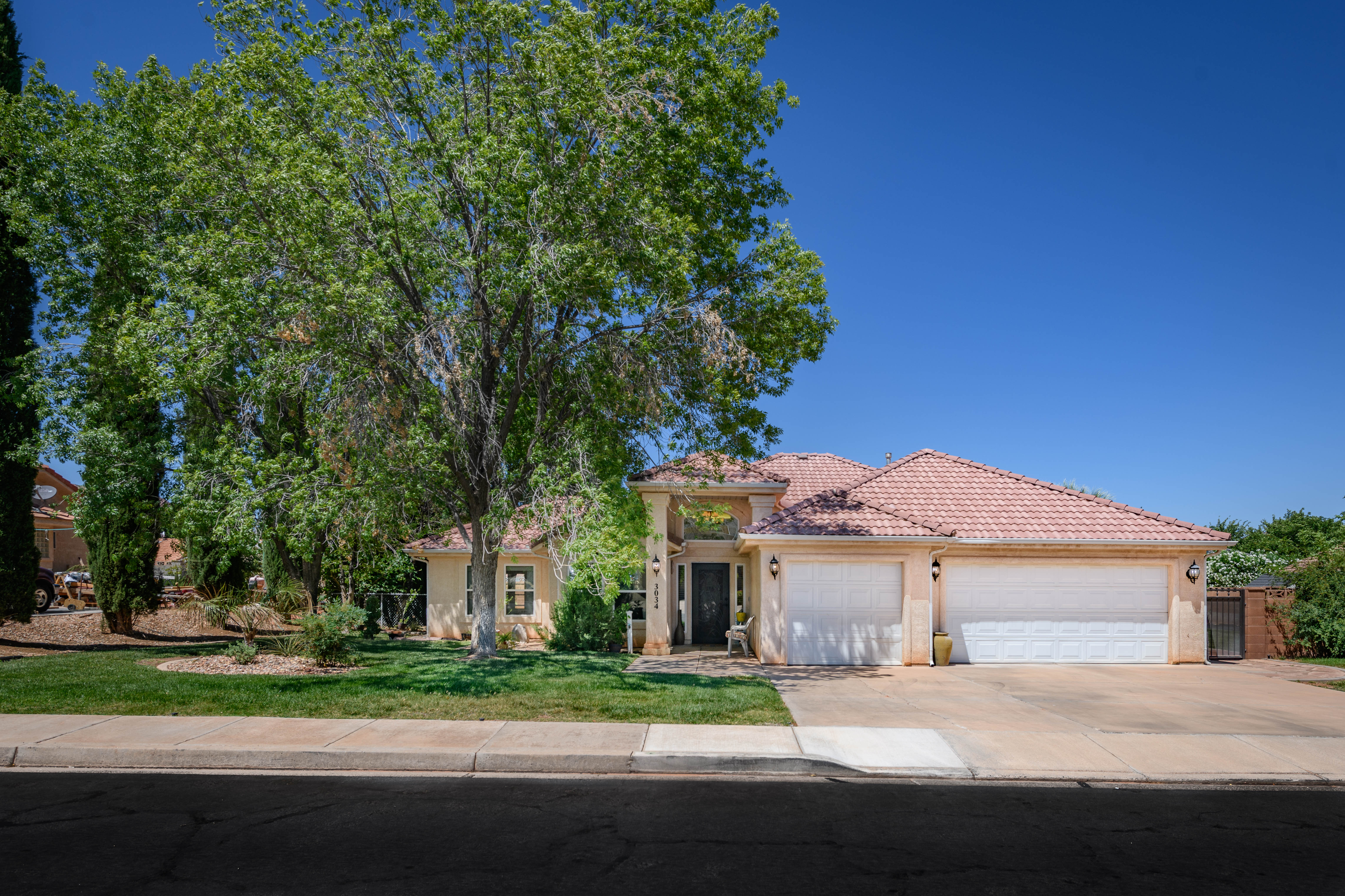 Single-story residence featuring a tile roof, stucco exterior, and an attached three-car garage