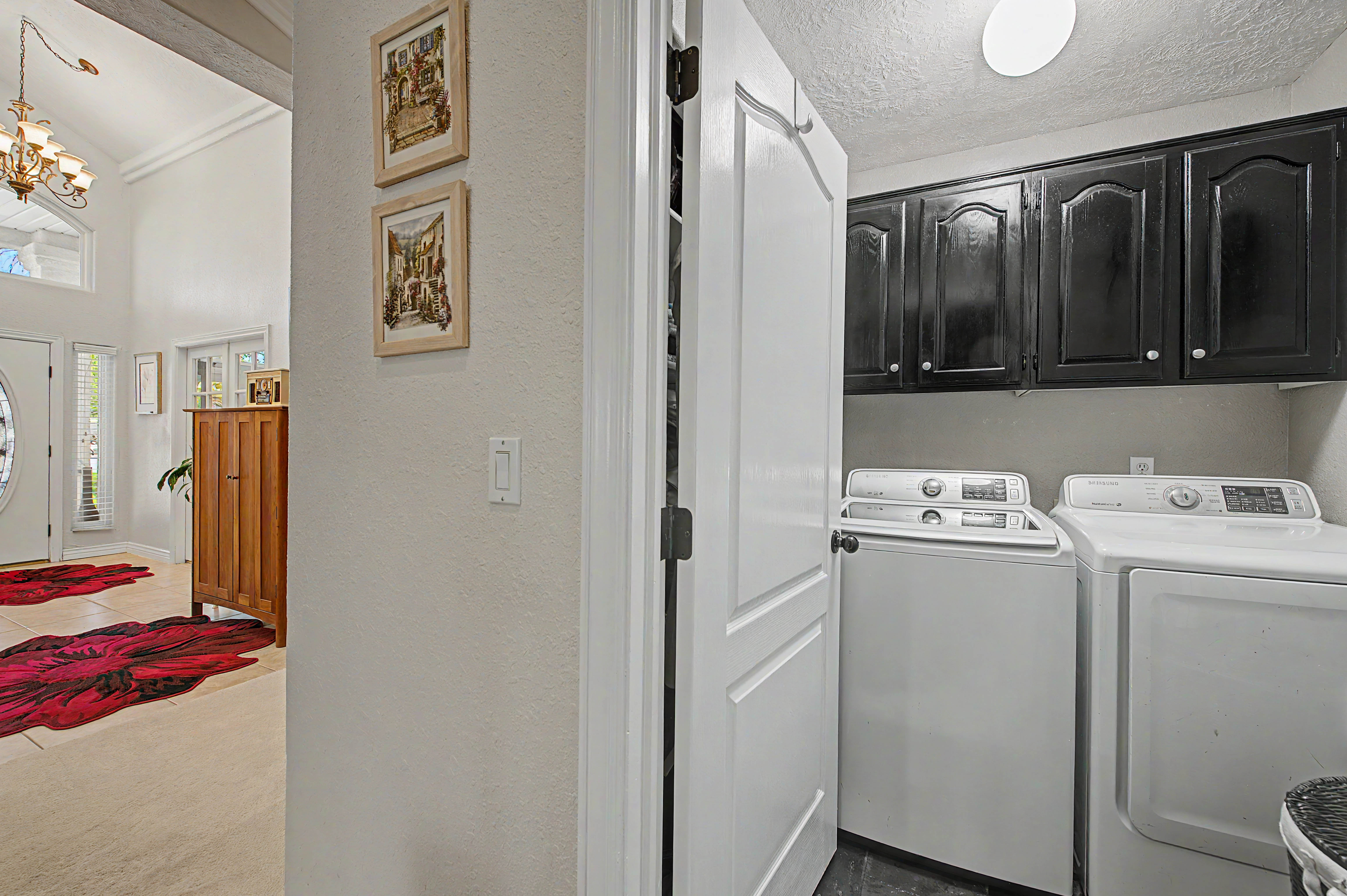 Dedicated laundry area featuring dark cabinetry, overhead lighting, and wood-finish flooring
