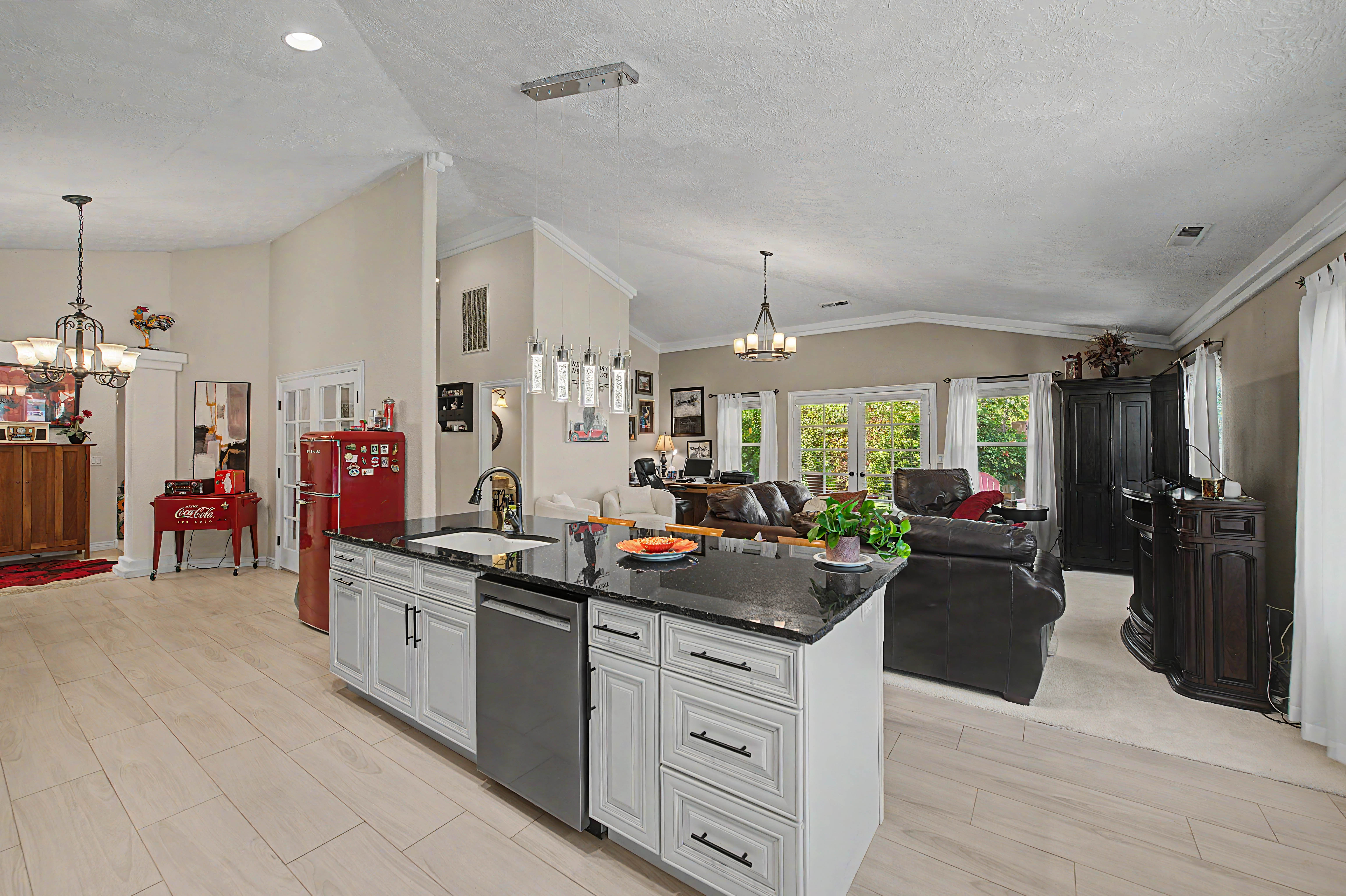 Kitchen island featuring a black countertop, integrated sink, and stainless steel dishwasher