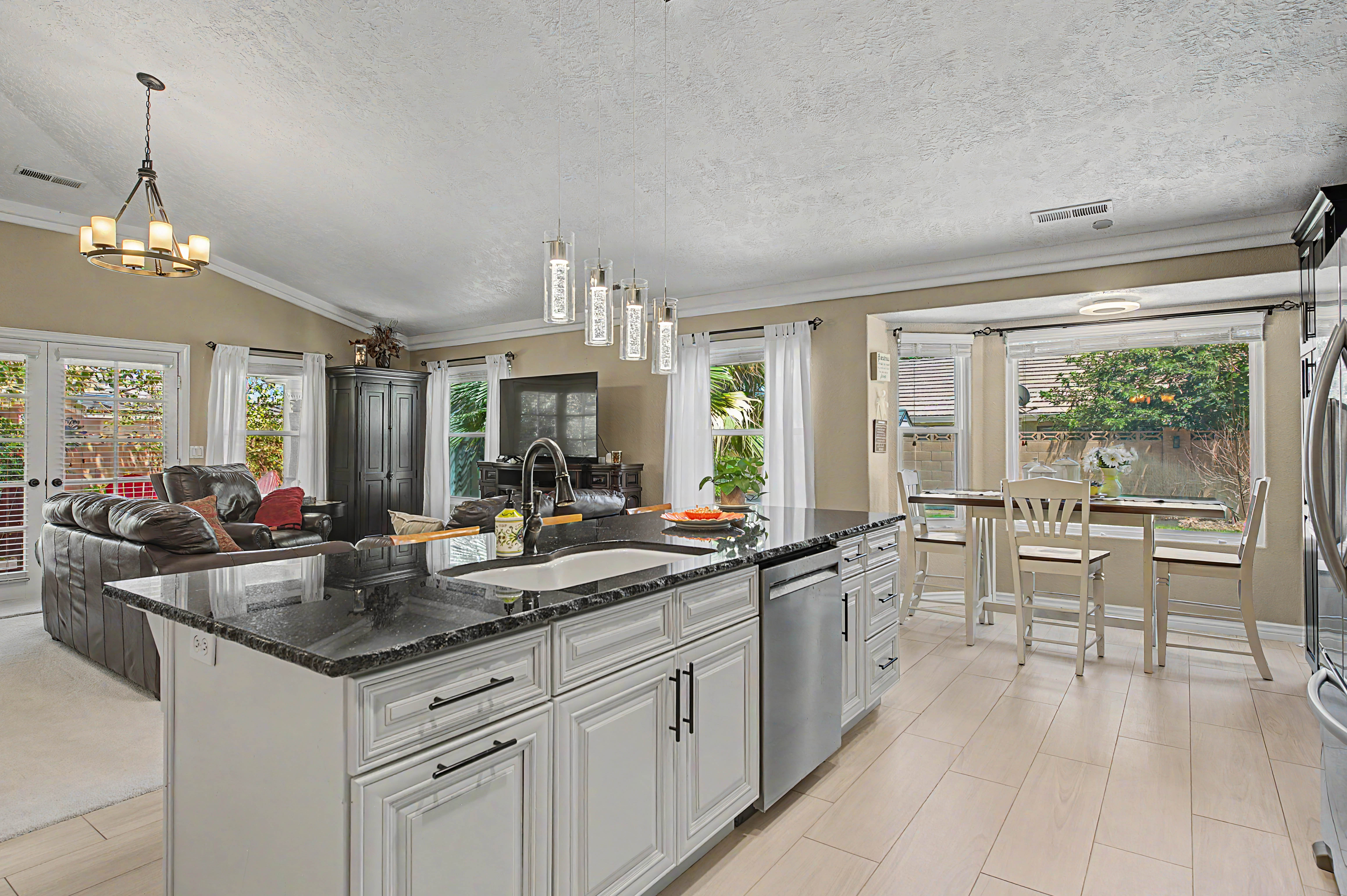Kitchen island with dark countertop, undermount sink, and stainless steel dishwasher