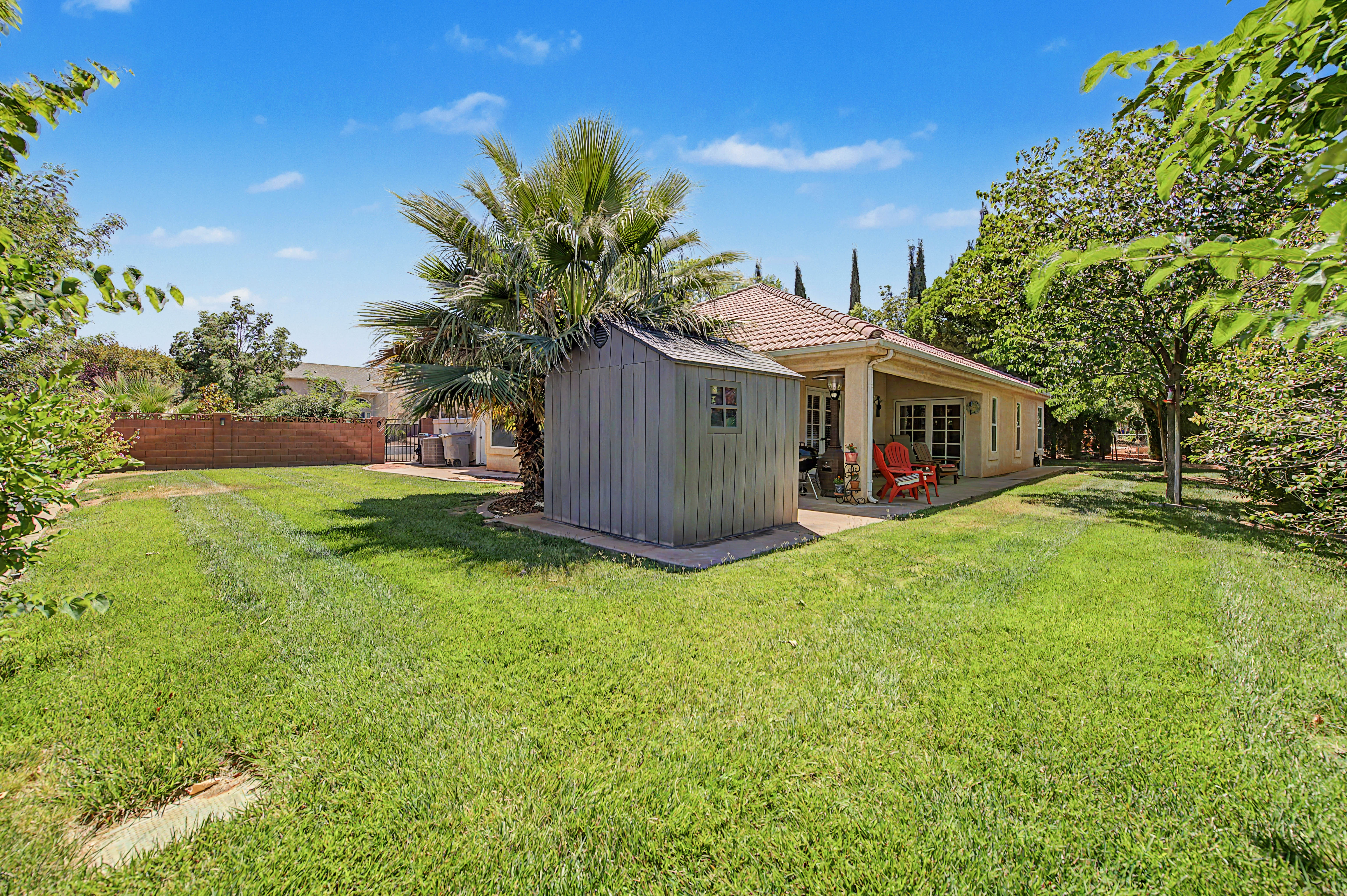 Expansive green lawn with mature trees and a privacy fence