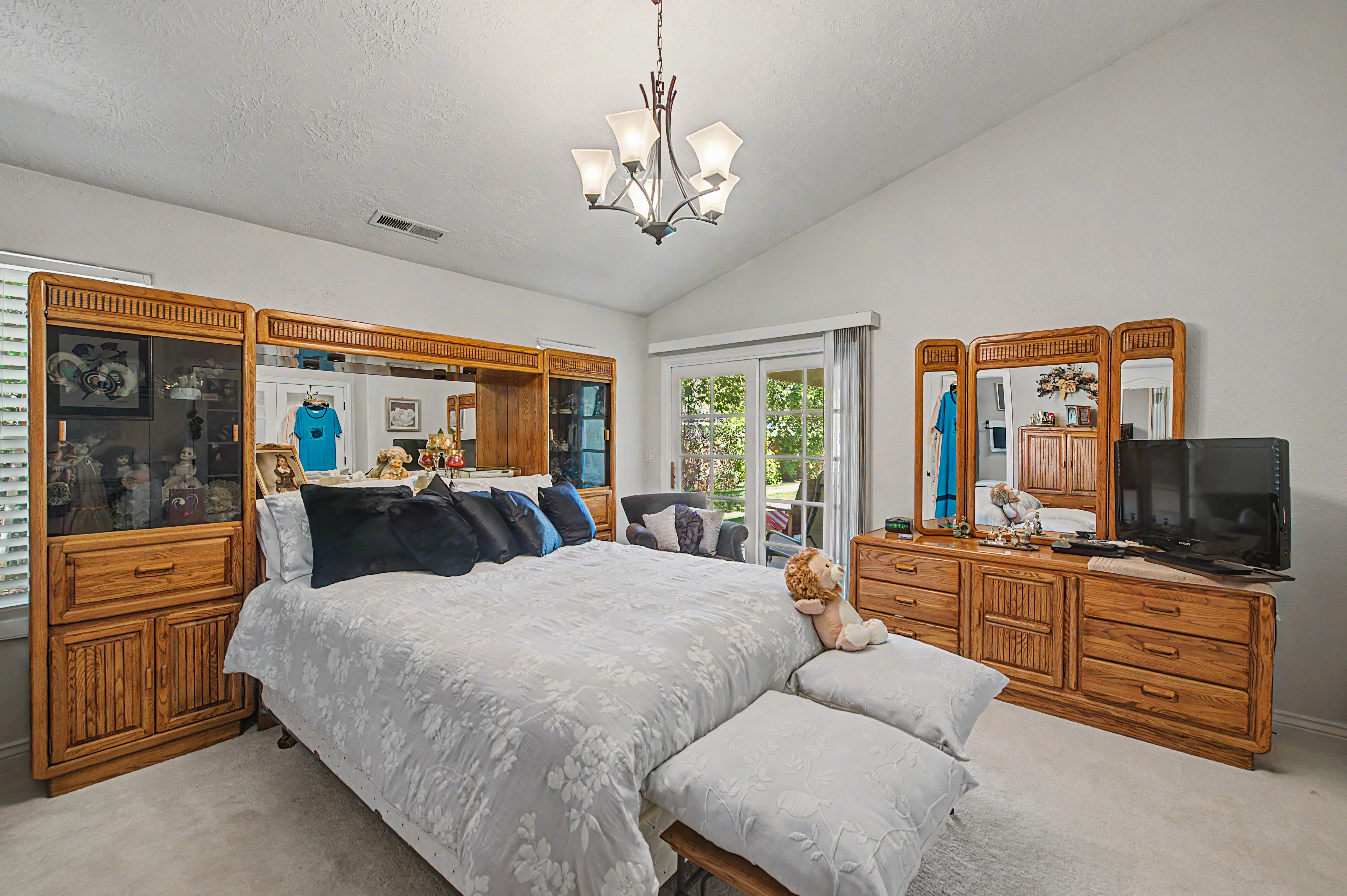 Vaulted ceiling bedroom with light-colored carpeting
