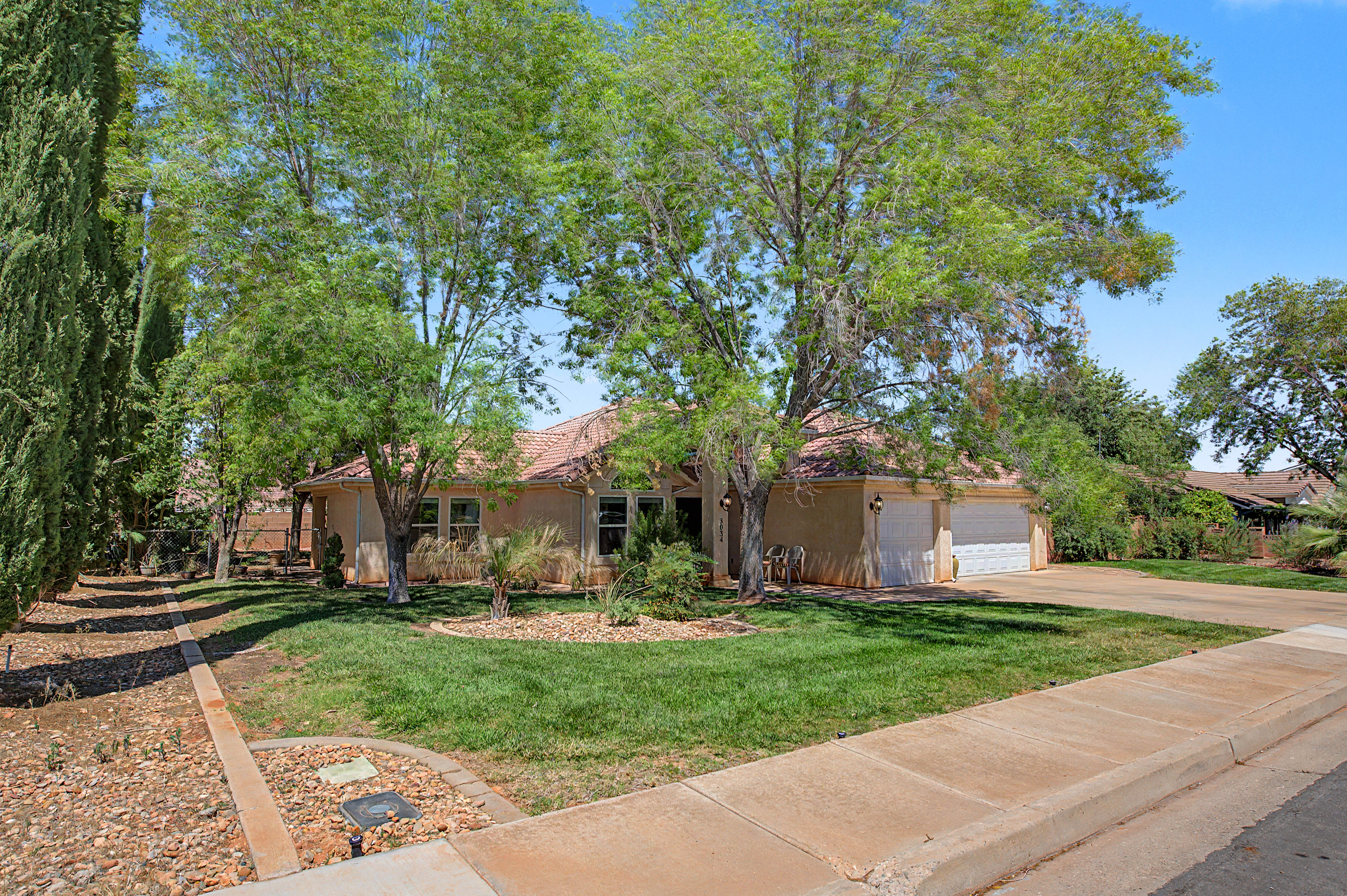 Stucco exterior residence with a tiled roof, featuring an attached two-car garage and a concrete driveway