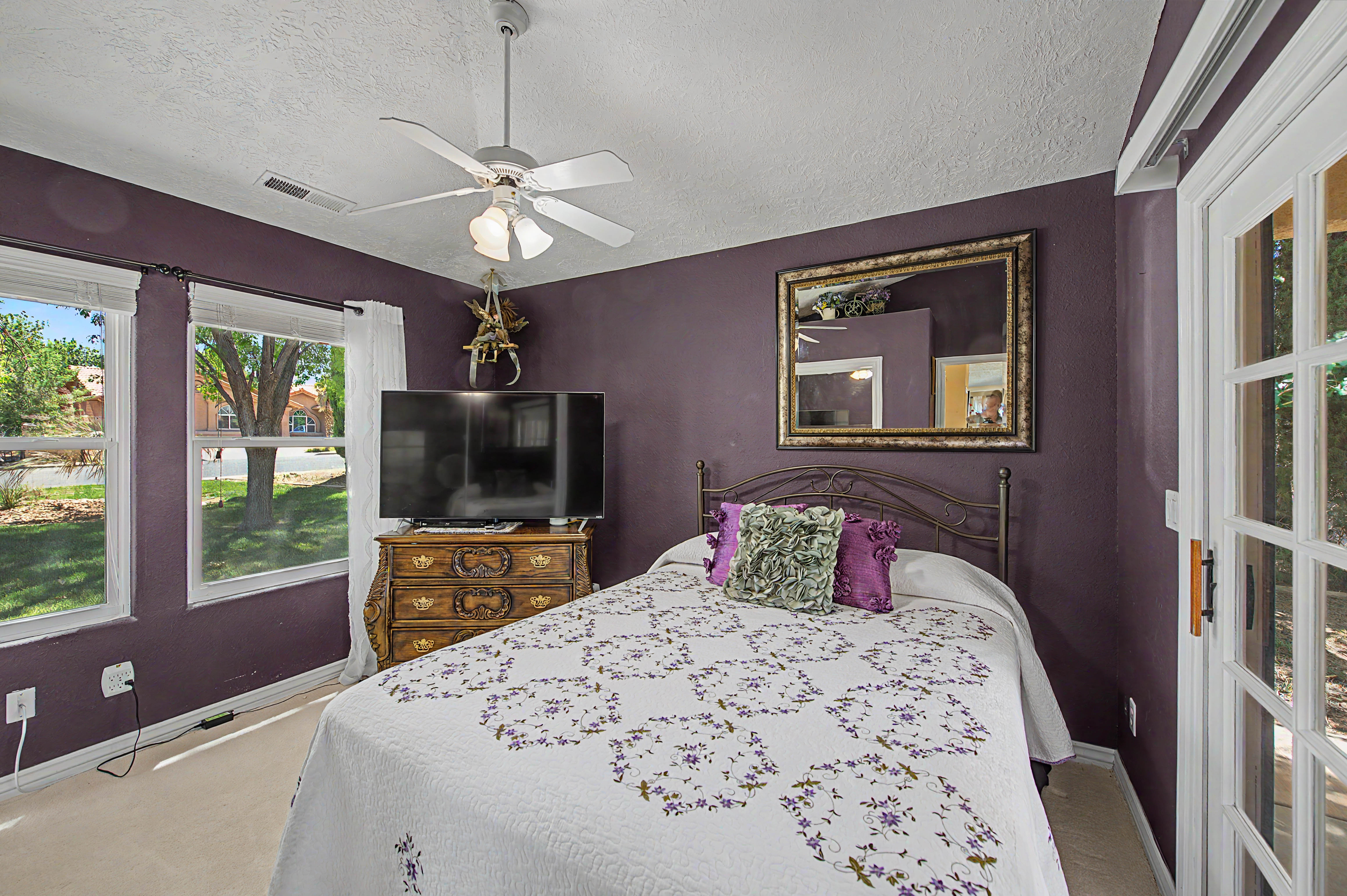 Carpeted interior space featuring a ceiling fan with integrated lighting, multiple windows providing natural illumination, and a French-style patio door with glass panels