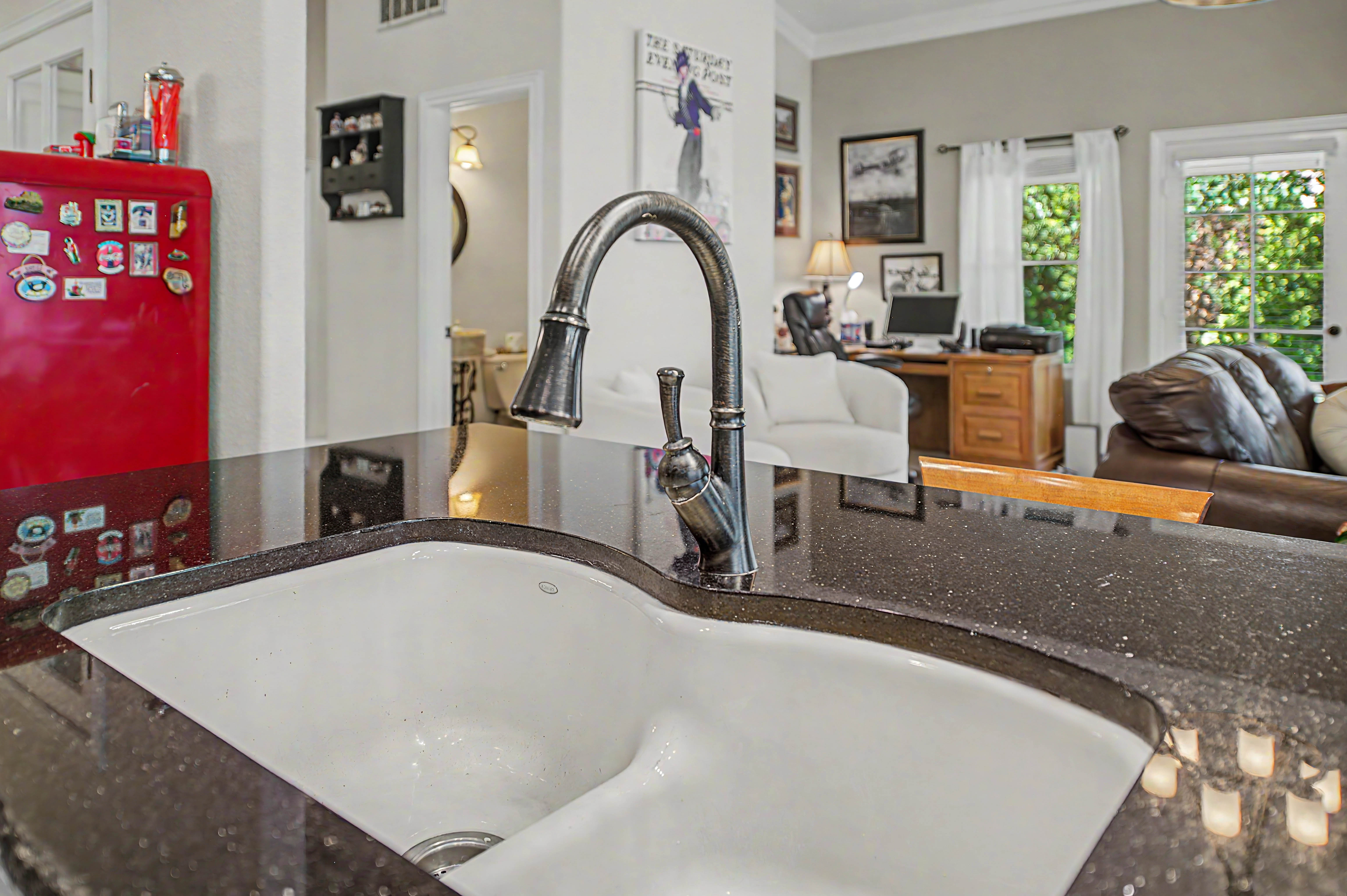 Kitchen sink featuring a dark speckled countertop, a white basin, and a gooseneck faucet