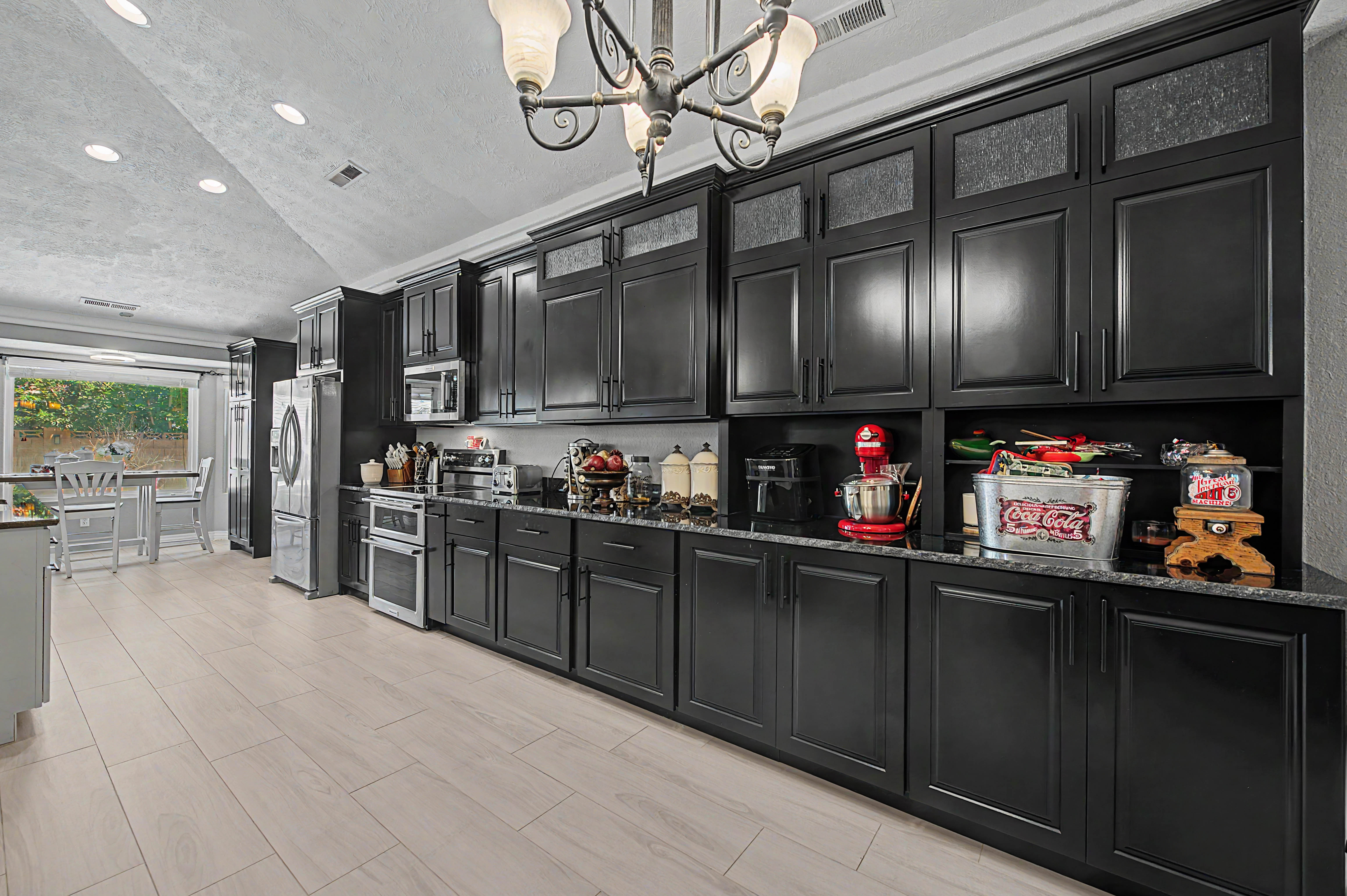 Kitchen featuring extensive black cabinetry, dark speckled countertops, and light wood-finish flooring