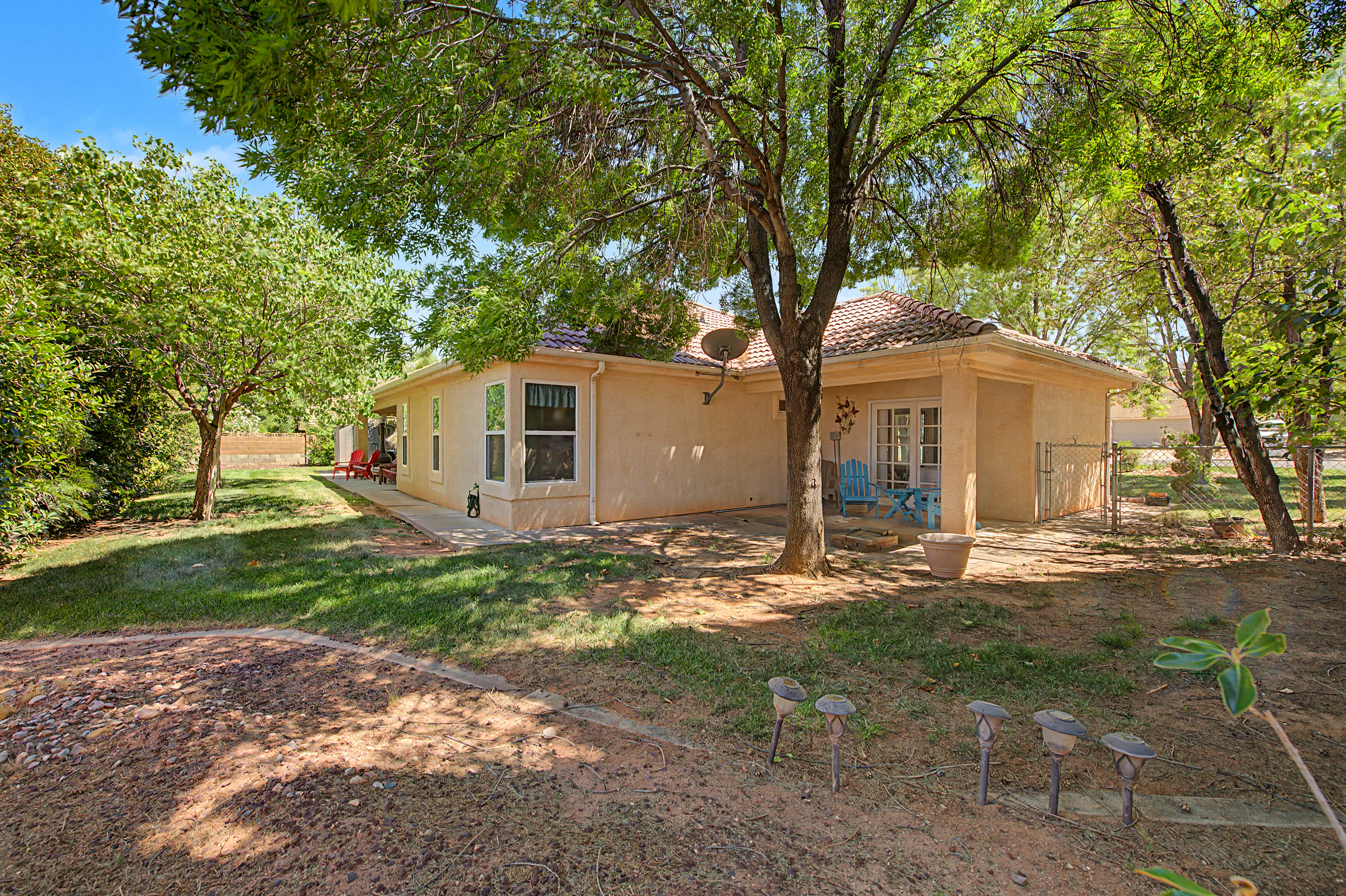 Expansive backyard featuring mature trees, a manicured lawn, and a concrete patio