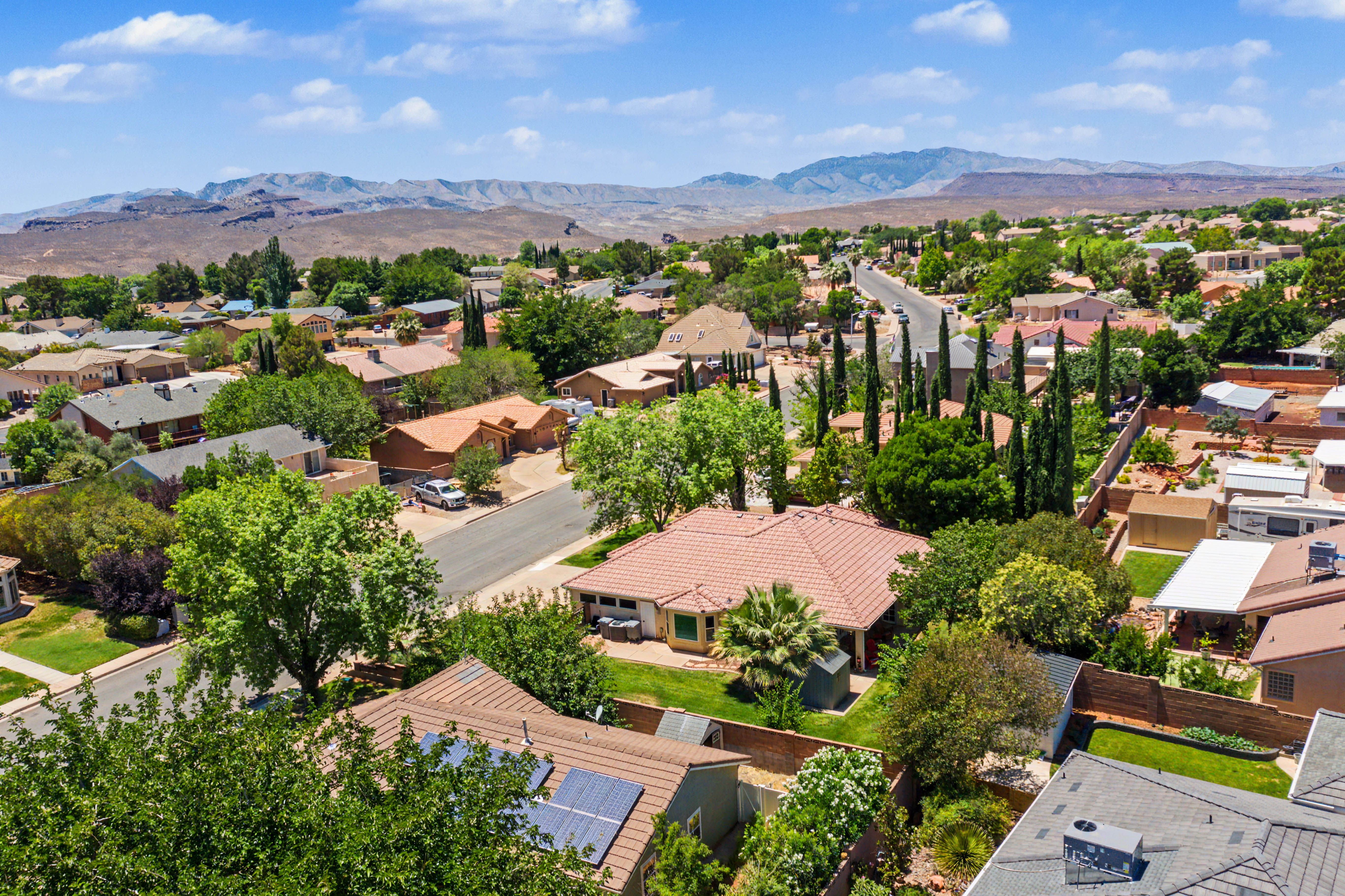 Residential neighborhood featuring mature landscaping, paved roadways, and a backdrop of distant mountains