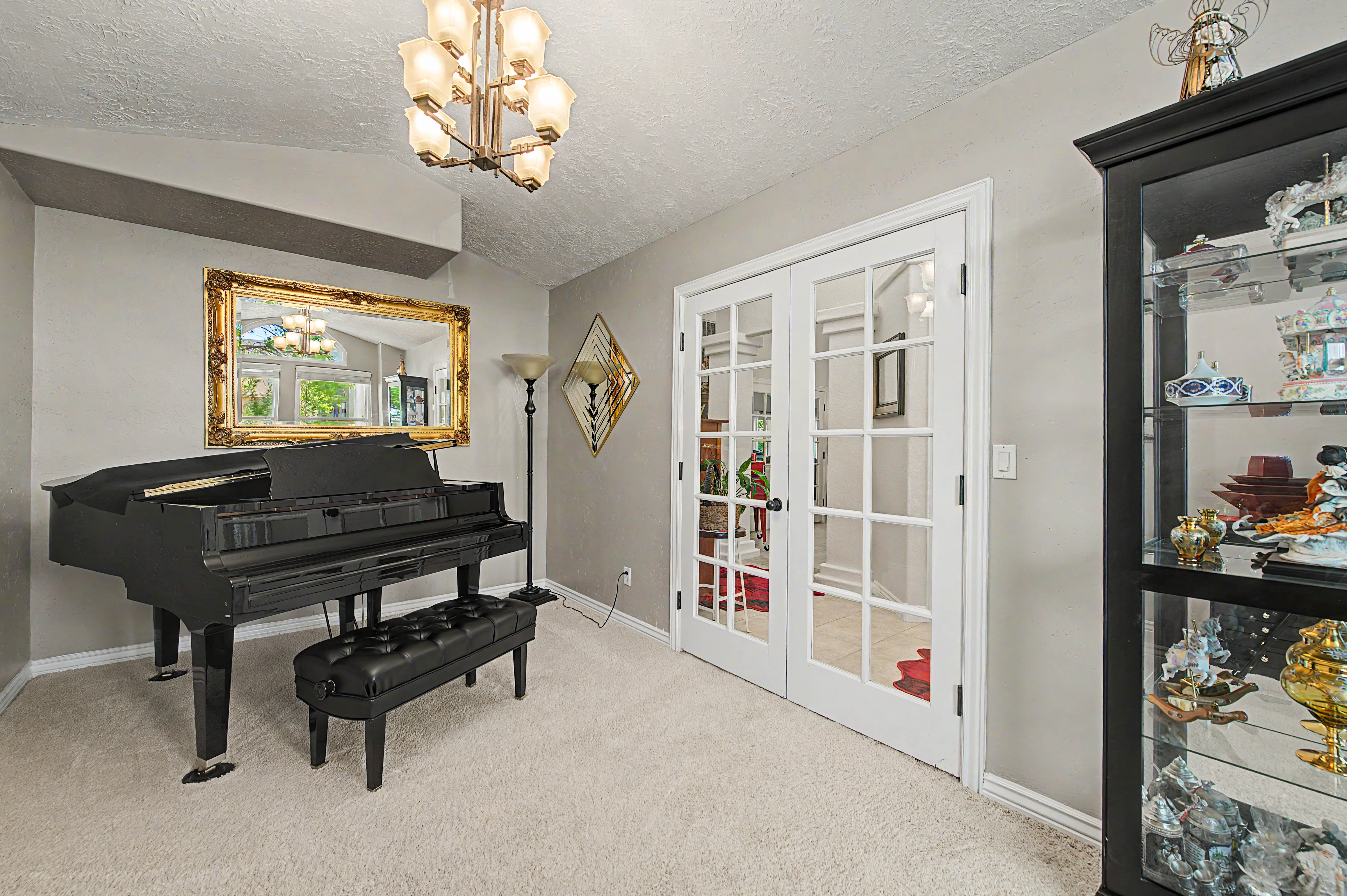 Spacious interior room featuring vaulted ceilings, plush carpet flooring, and a multi-bulb chandelier