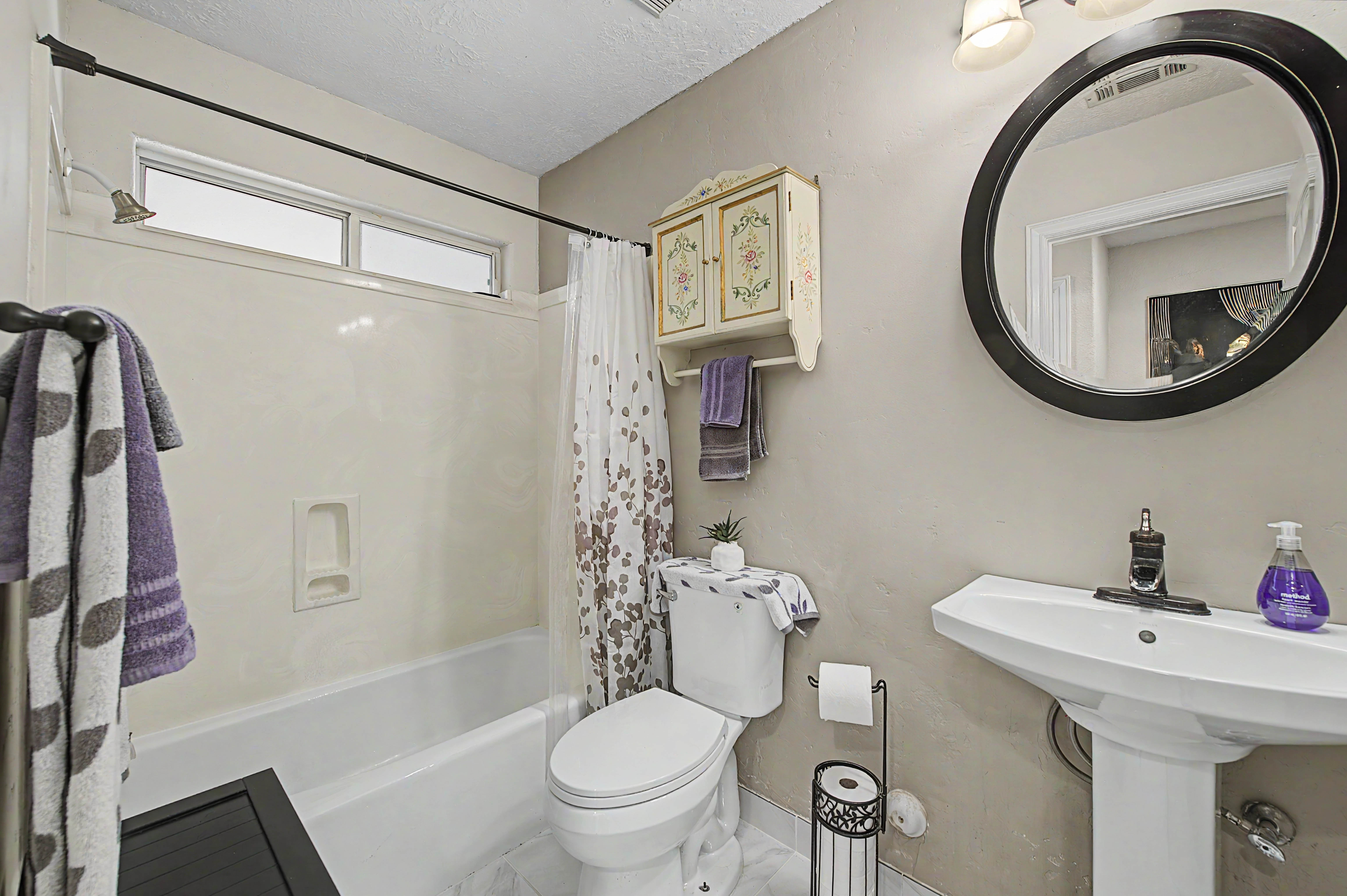 Bathroom featuring a pedestal sink, white toilet, and a bathtub with an integrated shower