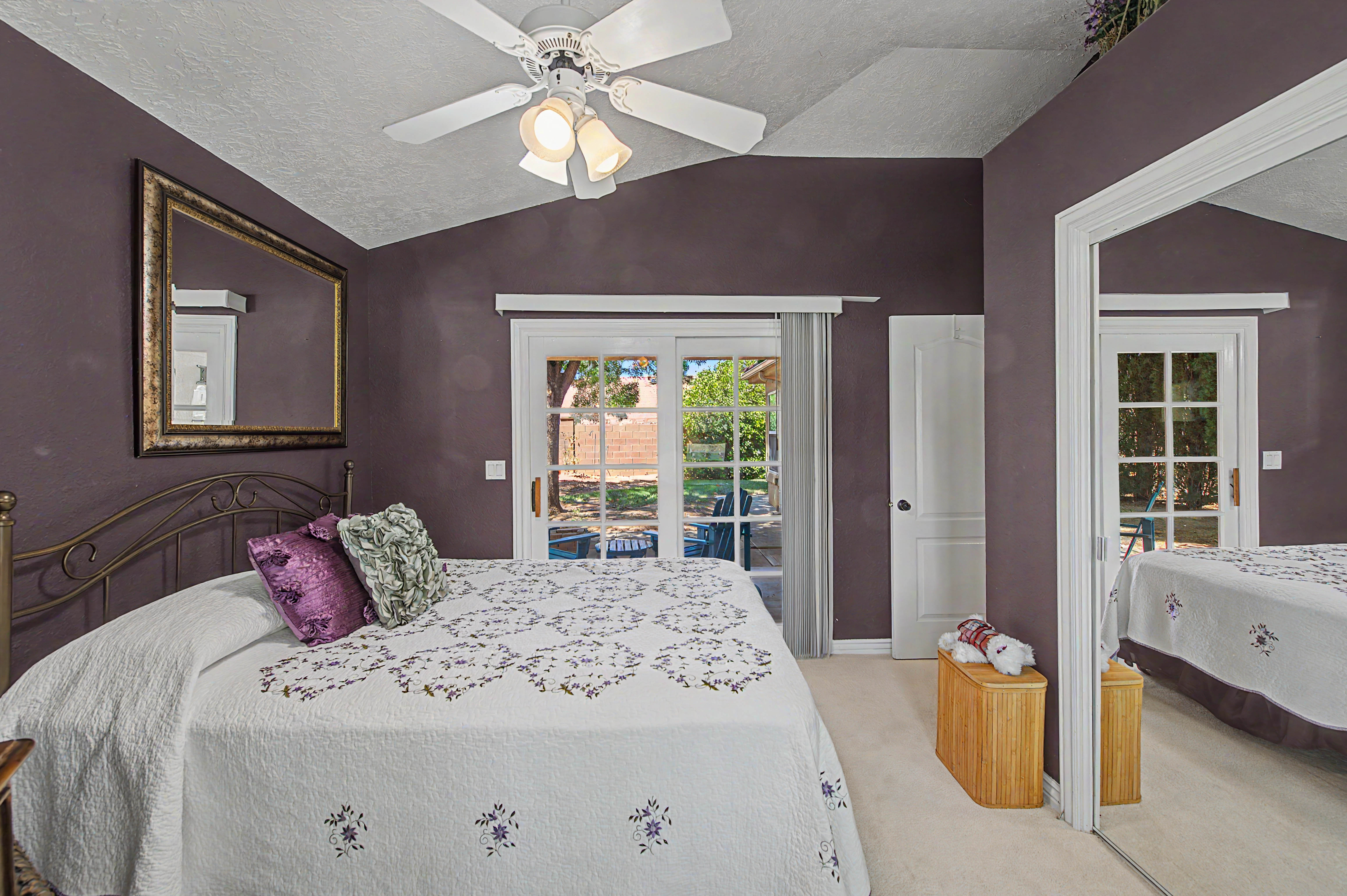 Vaulted ceiling room with an overhead fan, direct outdoor access via French doors, a full-height mirrored closet, and plush carpet flooring