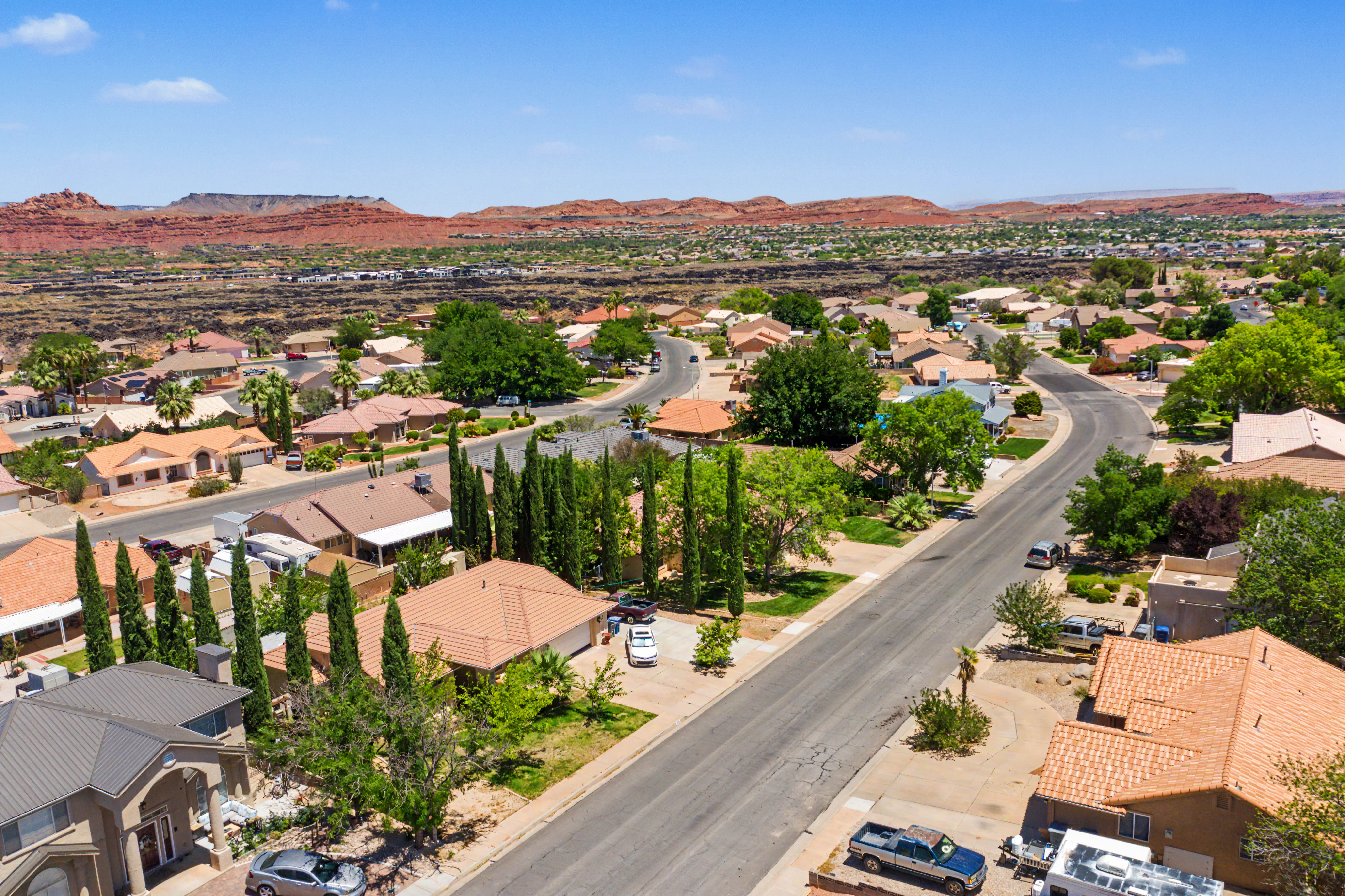 Residential neighborhood featuring a paved street, mature trees, and single-story homes with tile roofs