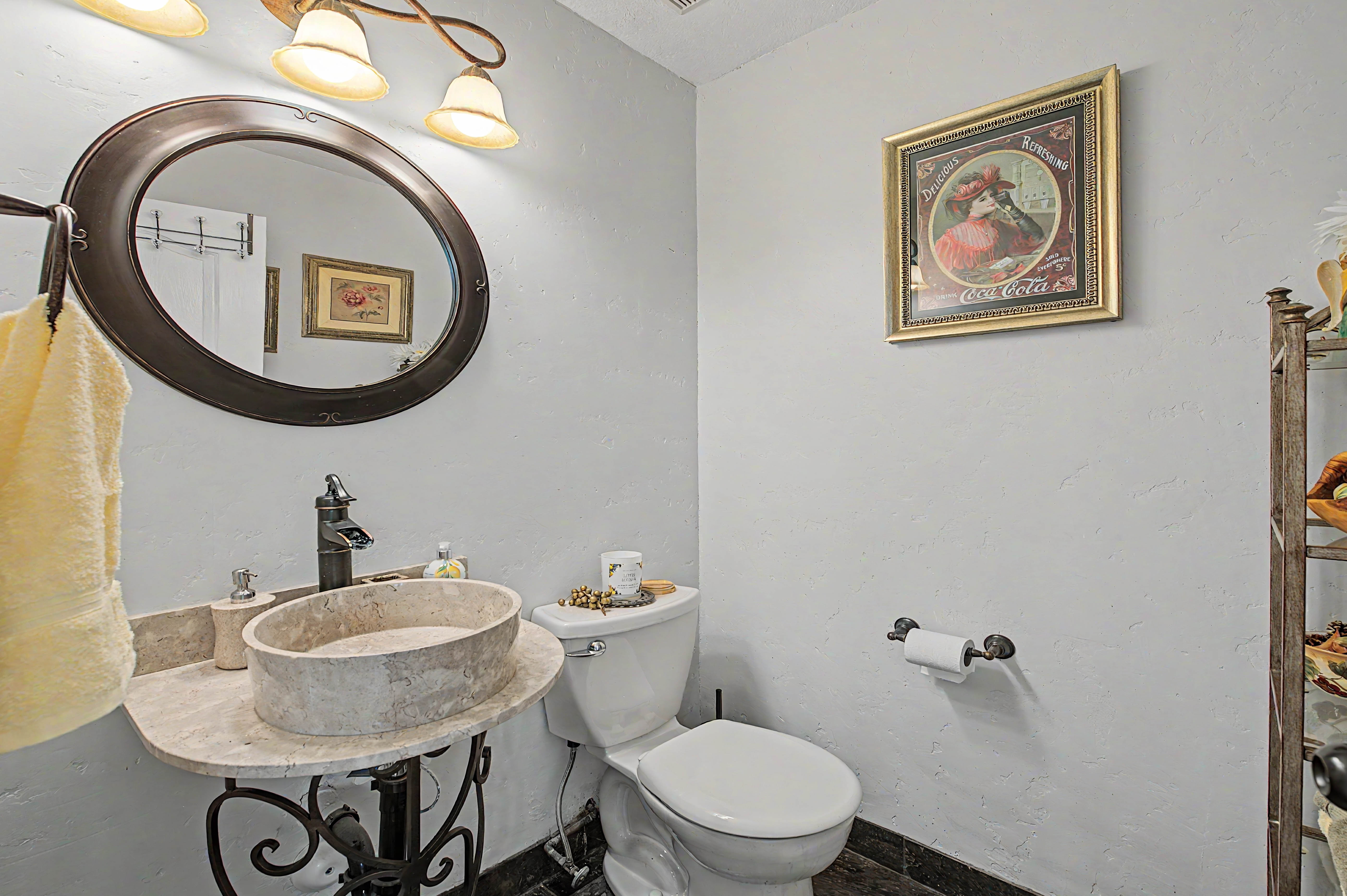 Bathroom featuring a stone vessel sink, dark bronze-finish faucet, and a round framed mirror