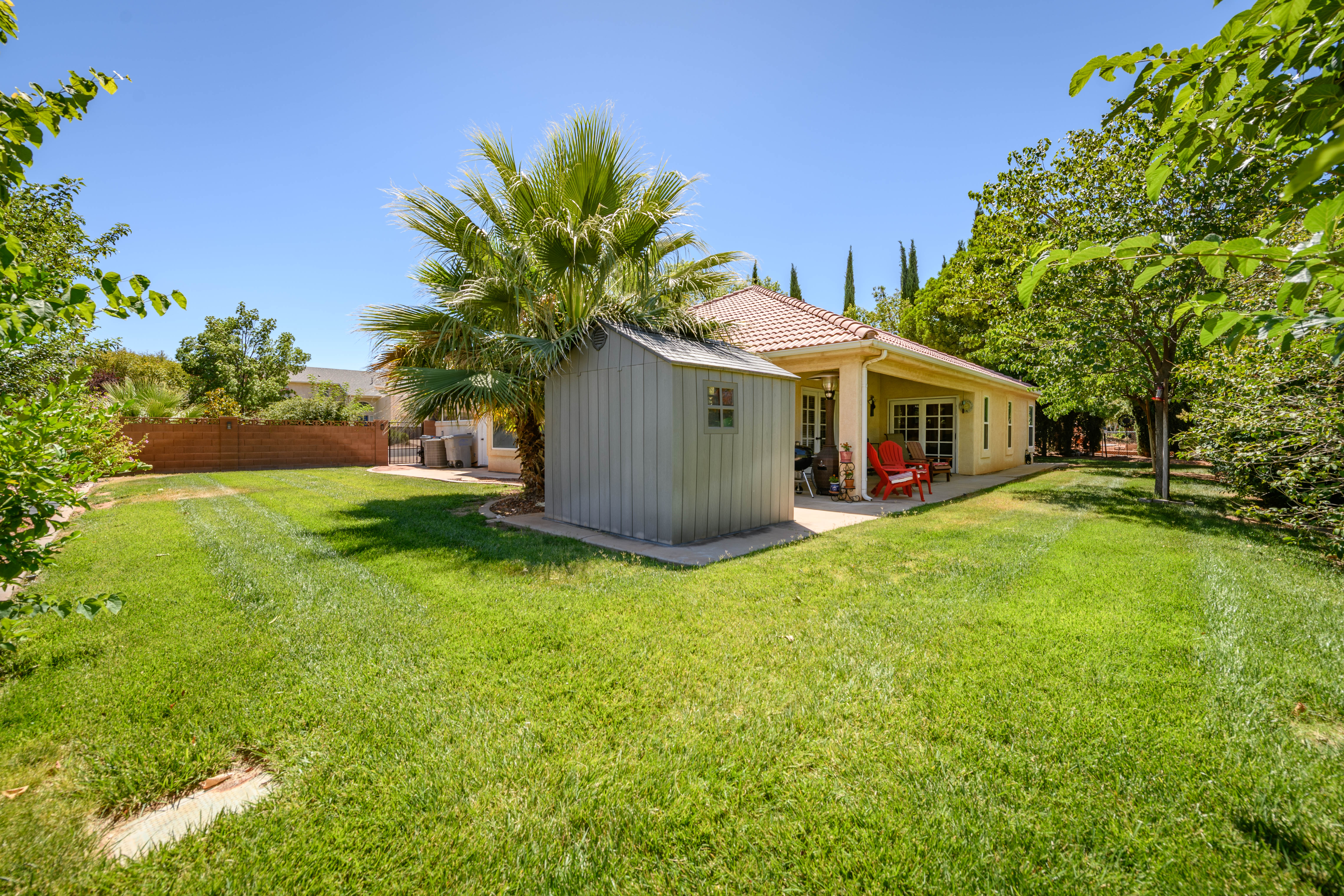 Expansive rear yard featuring a manicured lawn, established trees, and a detached storage shed