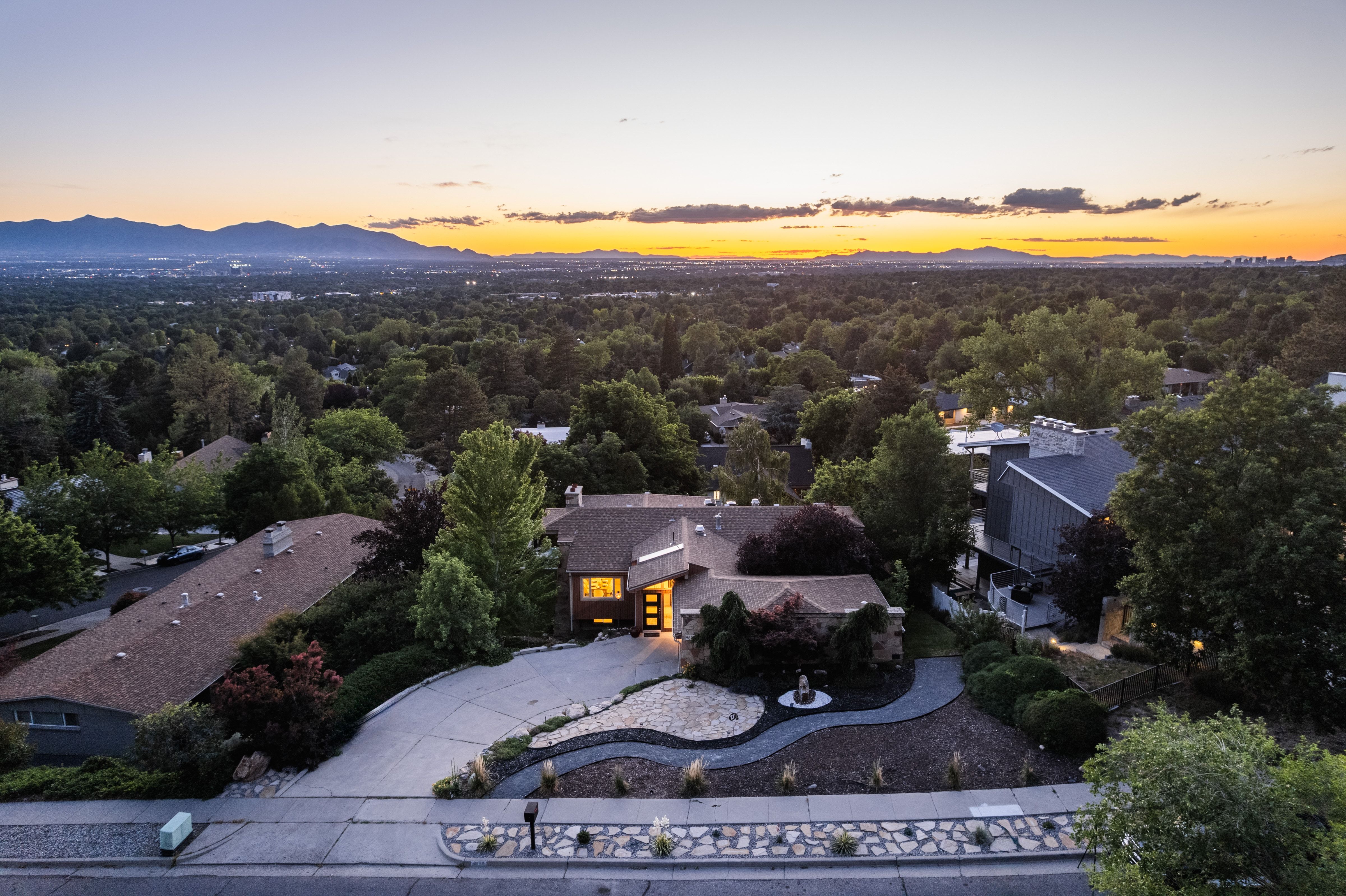 Expansive residential property featuring a curved driveway, mature landscaping, and a mountain backdrop