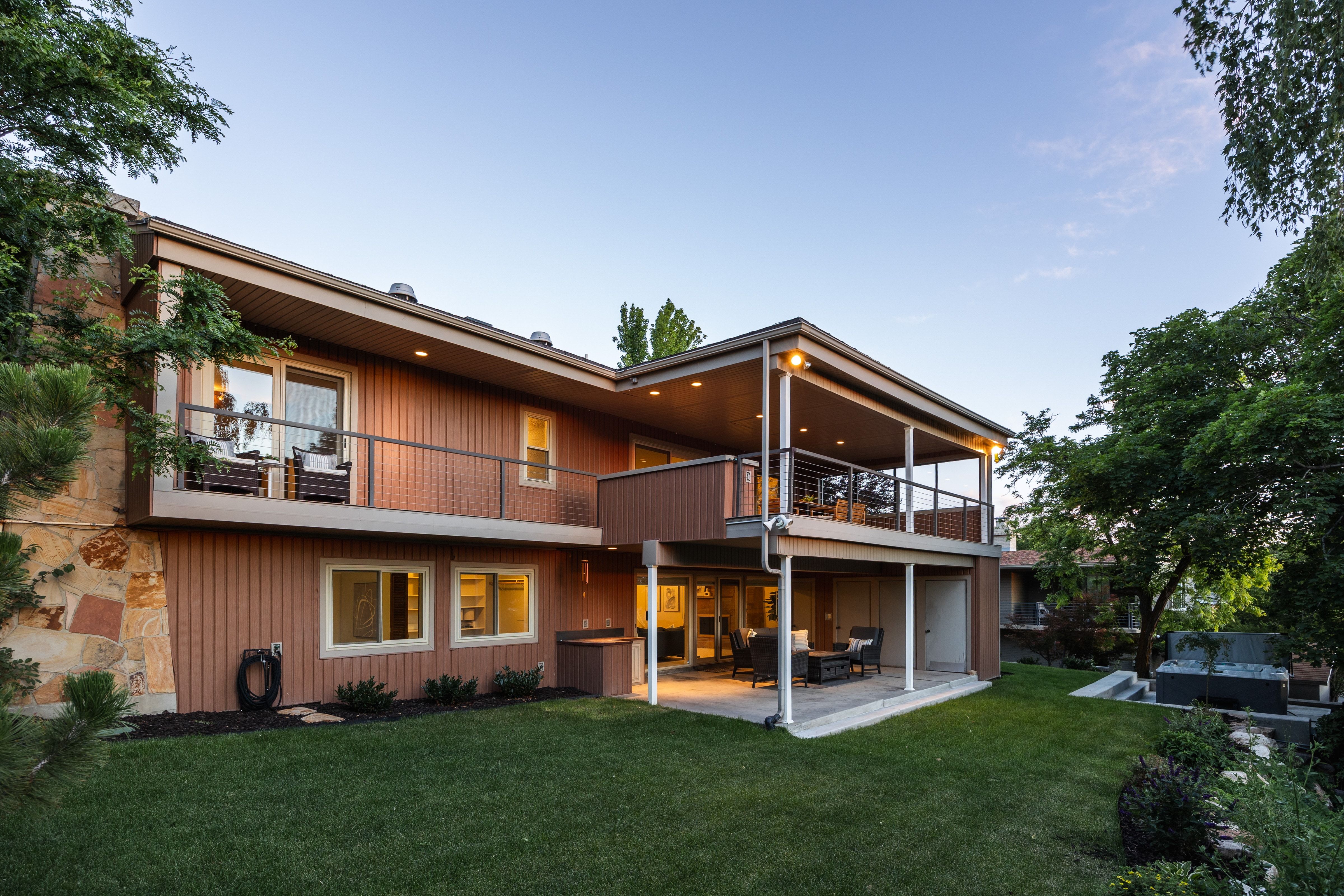Multi-level exterior featuring wood-paneled siding, stone accents, and a covered patio