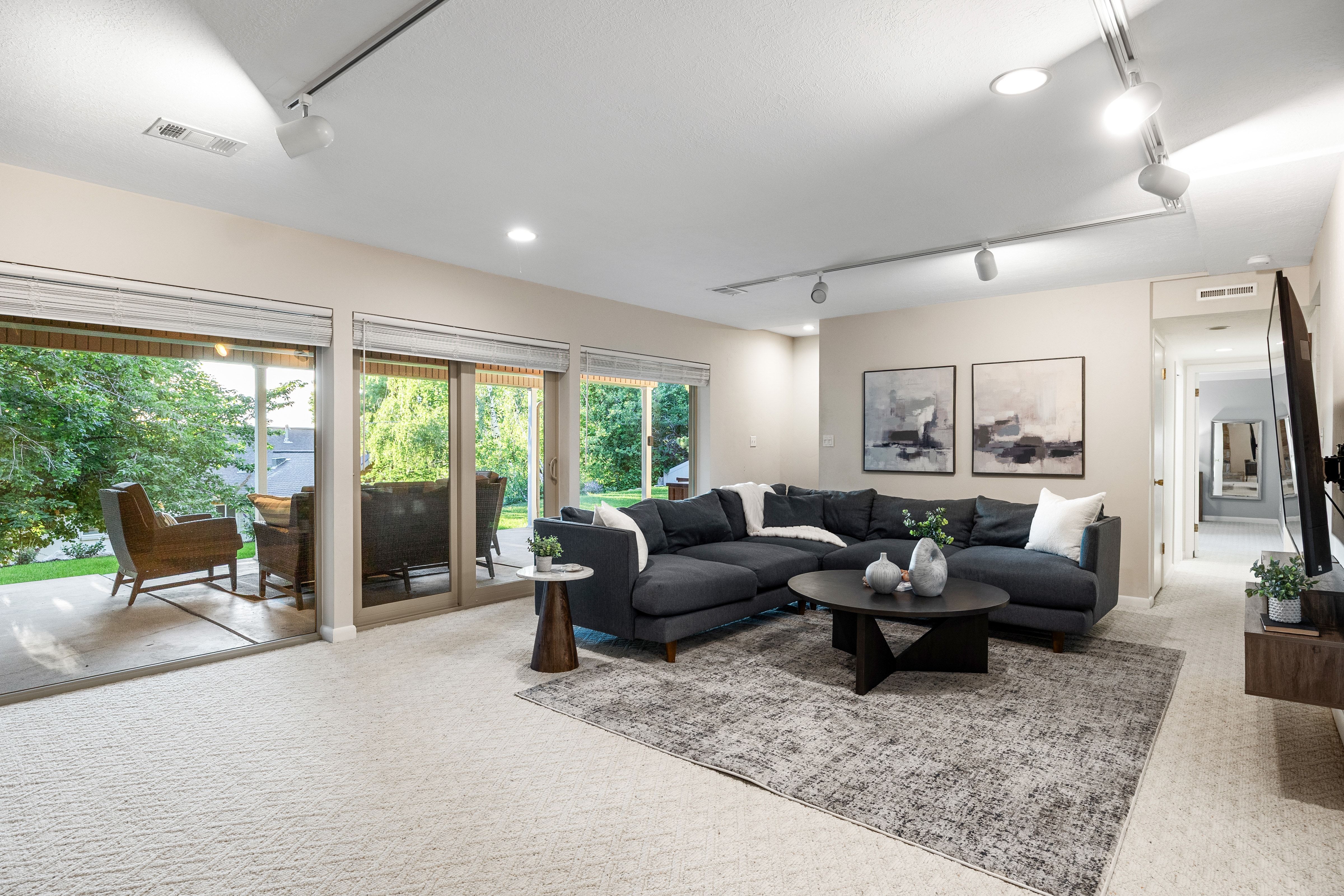 Expansive living space featuring a wall of multiple glass sliding doors, recessed lighting, track lighting, light-toned wall paint, and light-toned patterned carpeting