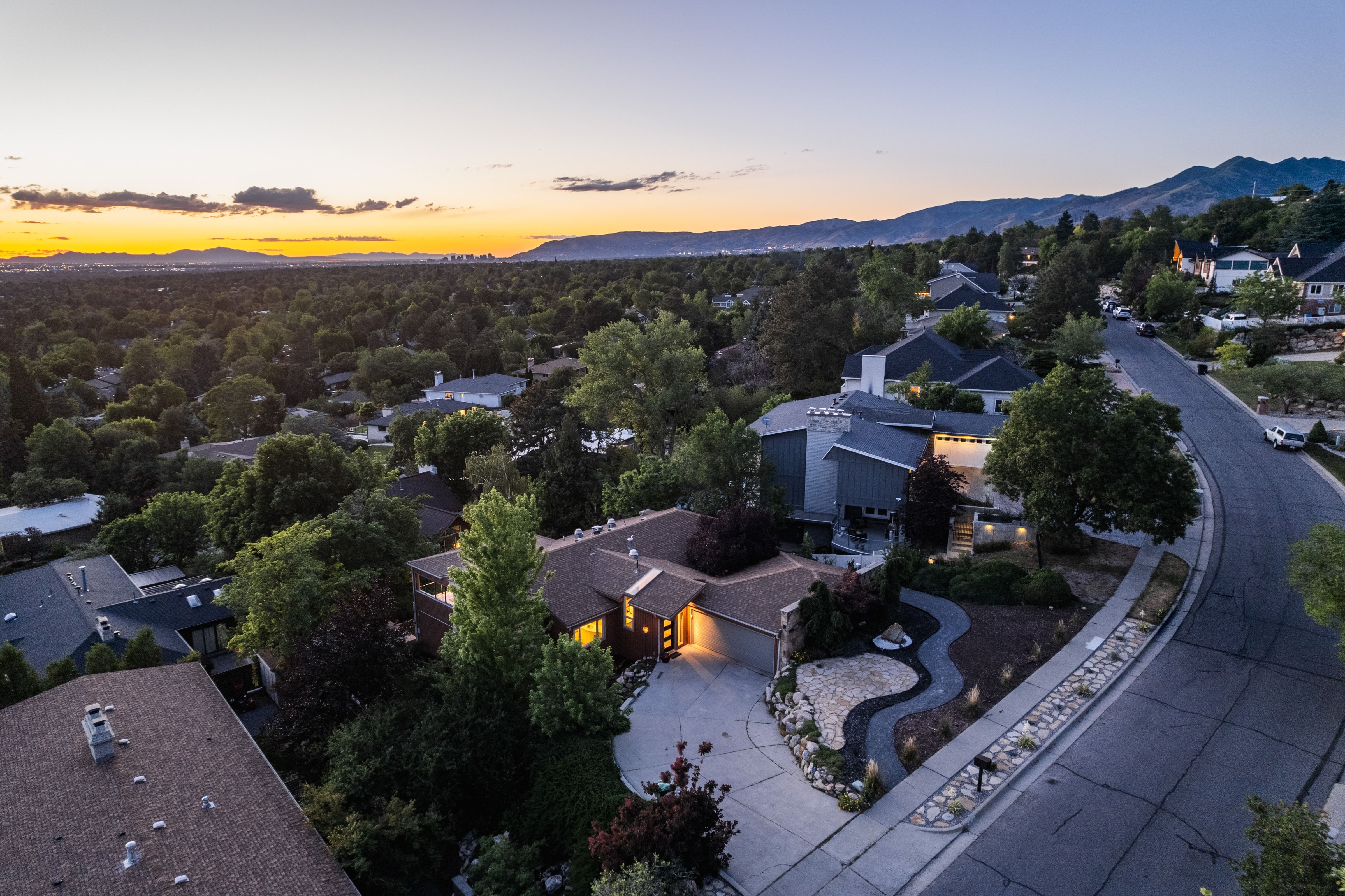 Residential property featuring a paved driveway, integrated garage, and a manicured front yard with stone landscaping