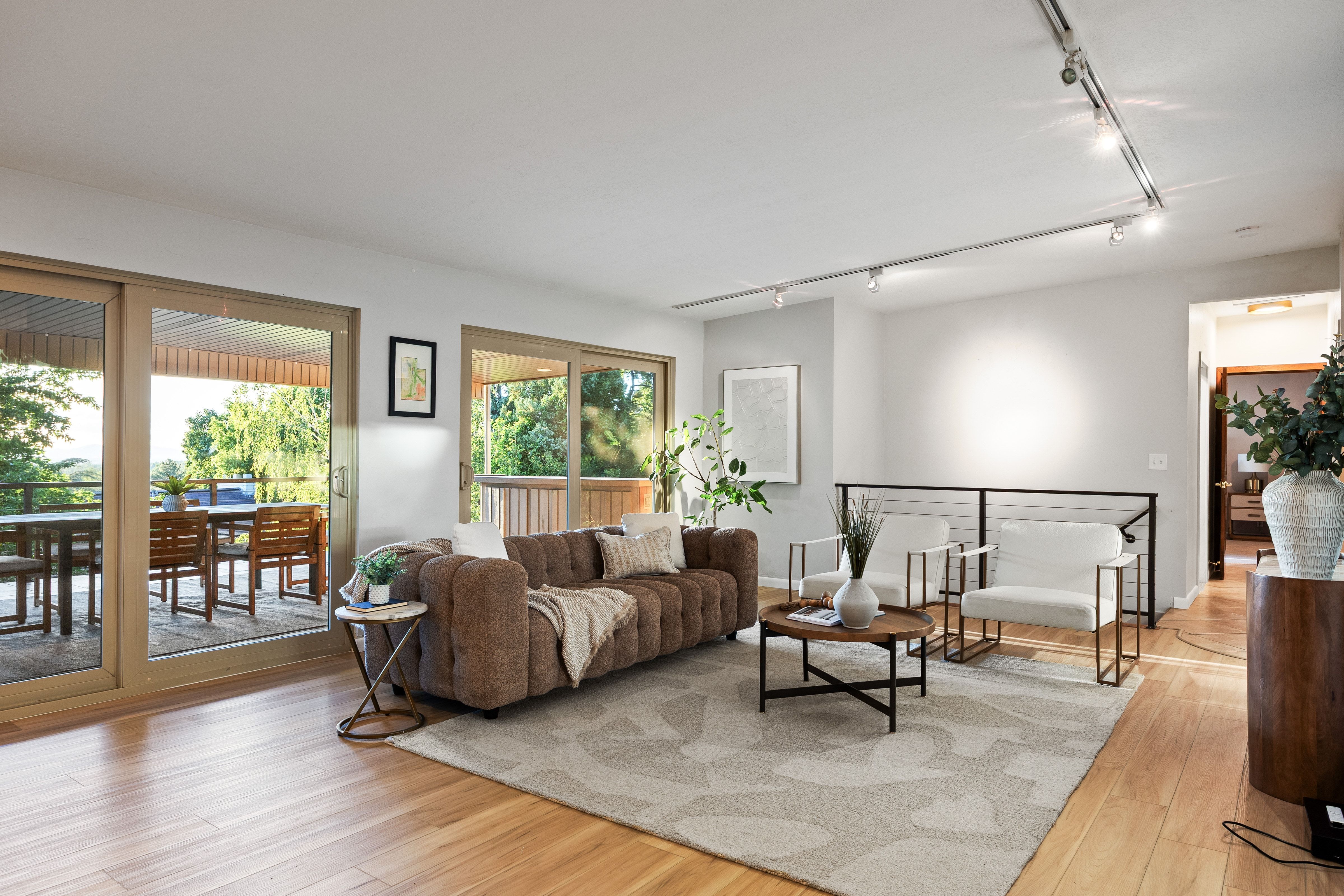 Bright living space featuring natural wood-finish flooring and track lighting