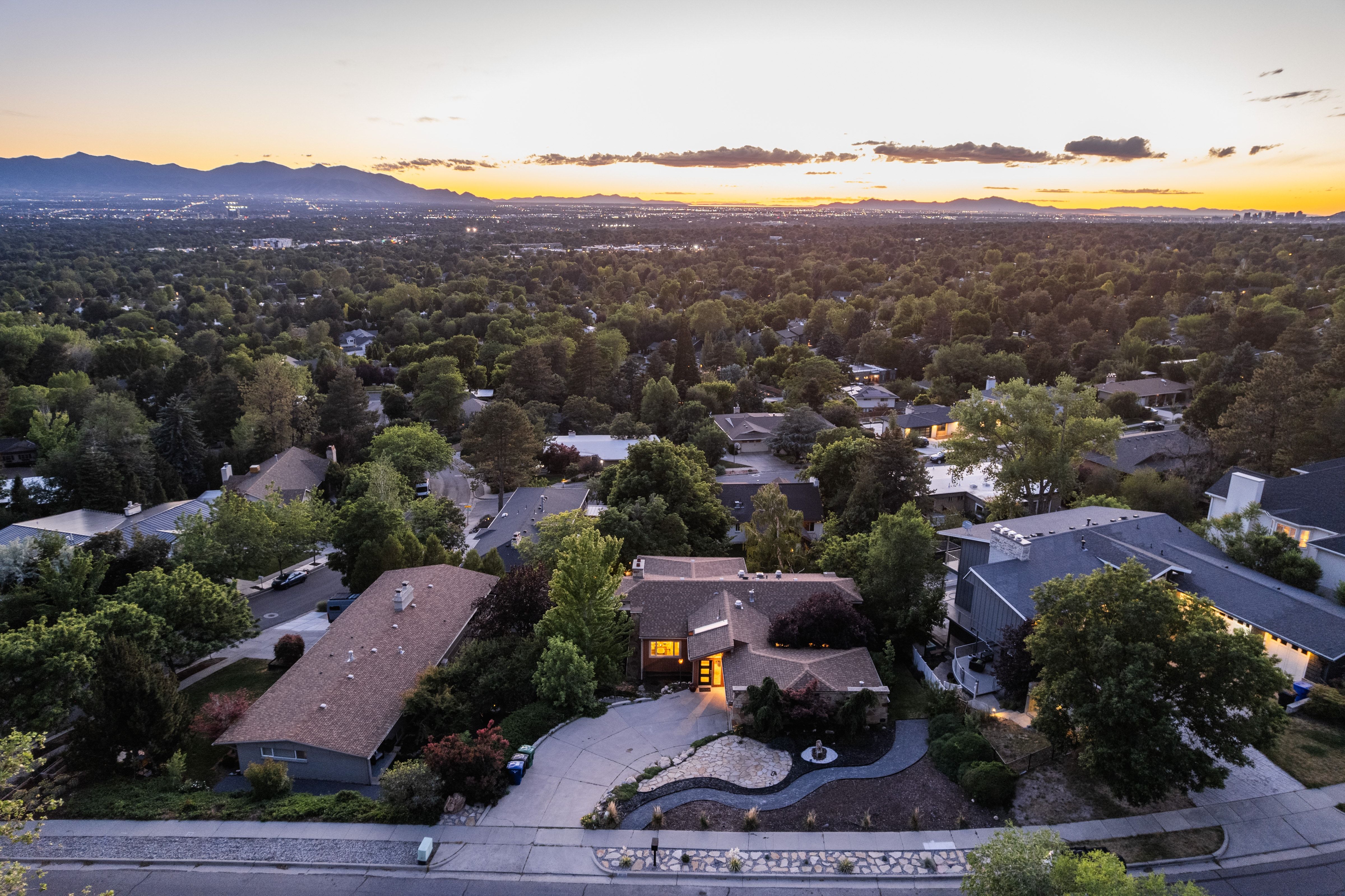 The property features an expansive lot with mature trees, a multi-car driveway, and a distinct architectural style