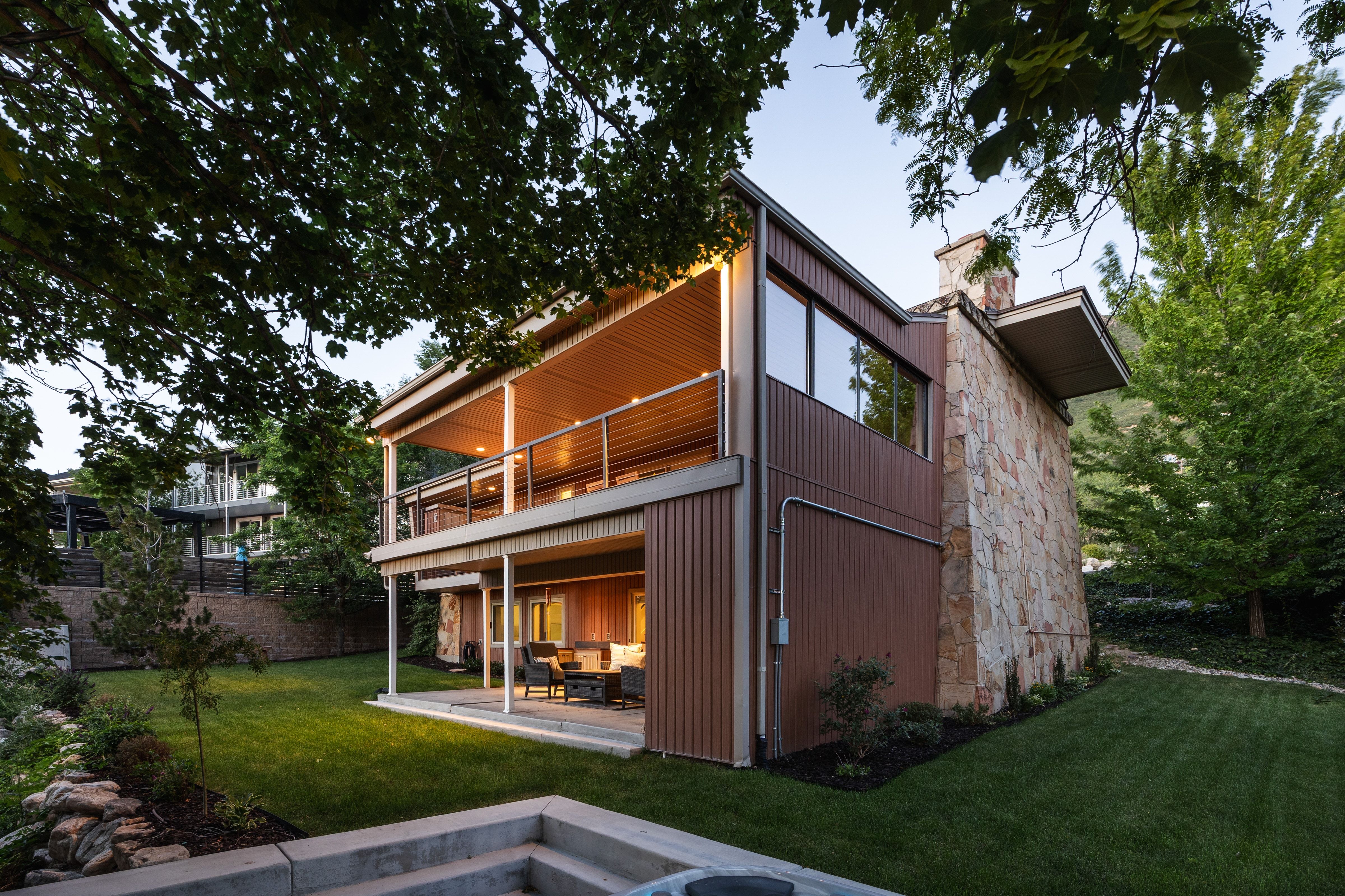 Multi-level exterior featuring a stone accent wall, corrugated panel siding, and a covered upper-level balcony with metal railings