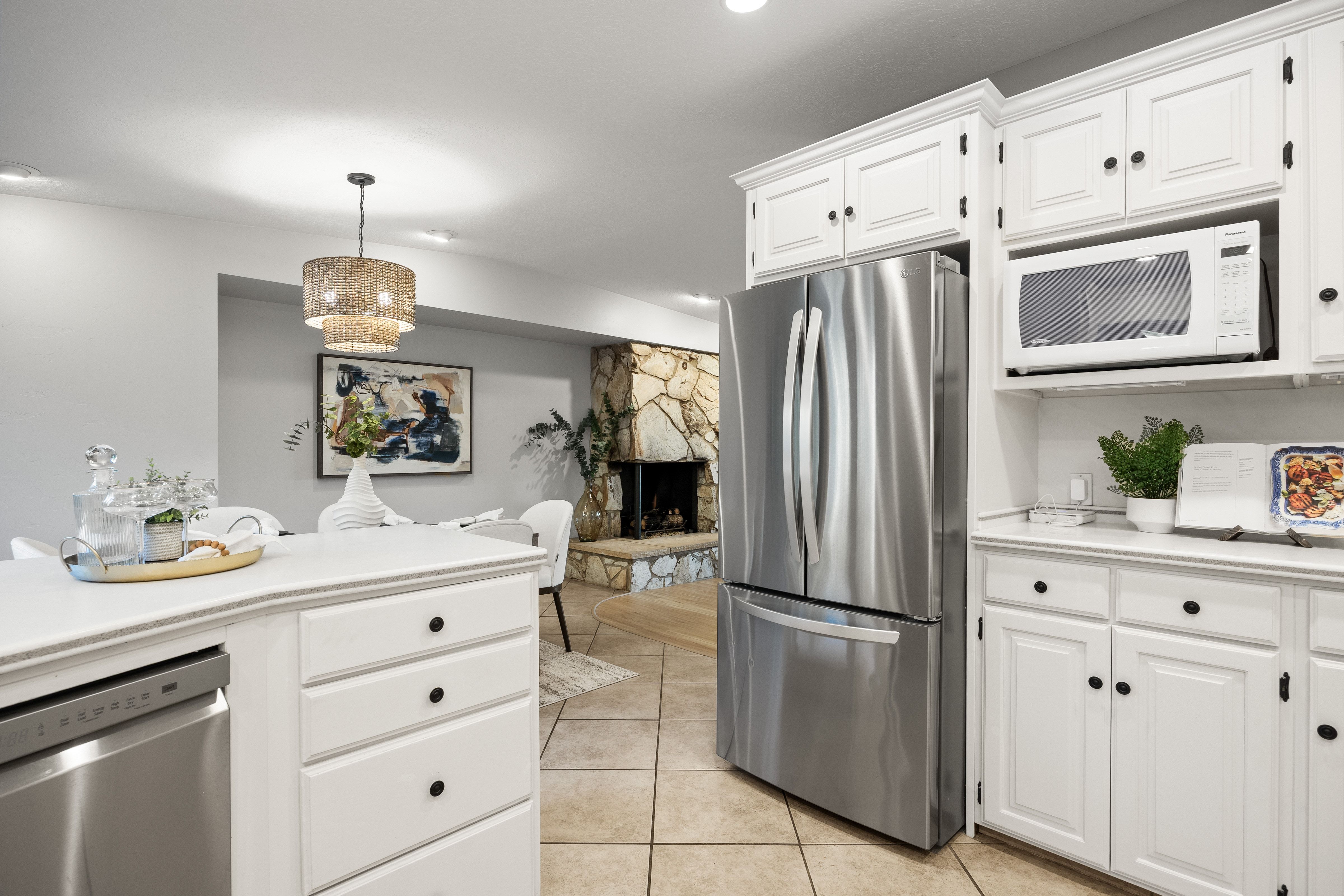 Kitchen featuring white cabinetry with black hardware, stainless steel French-door refrigerator, and integrated microwave