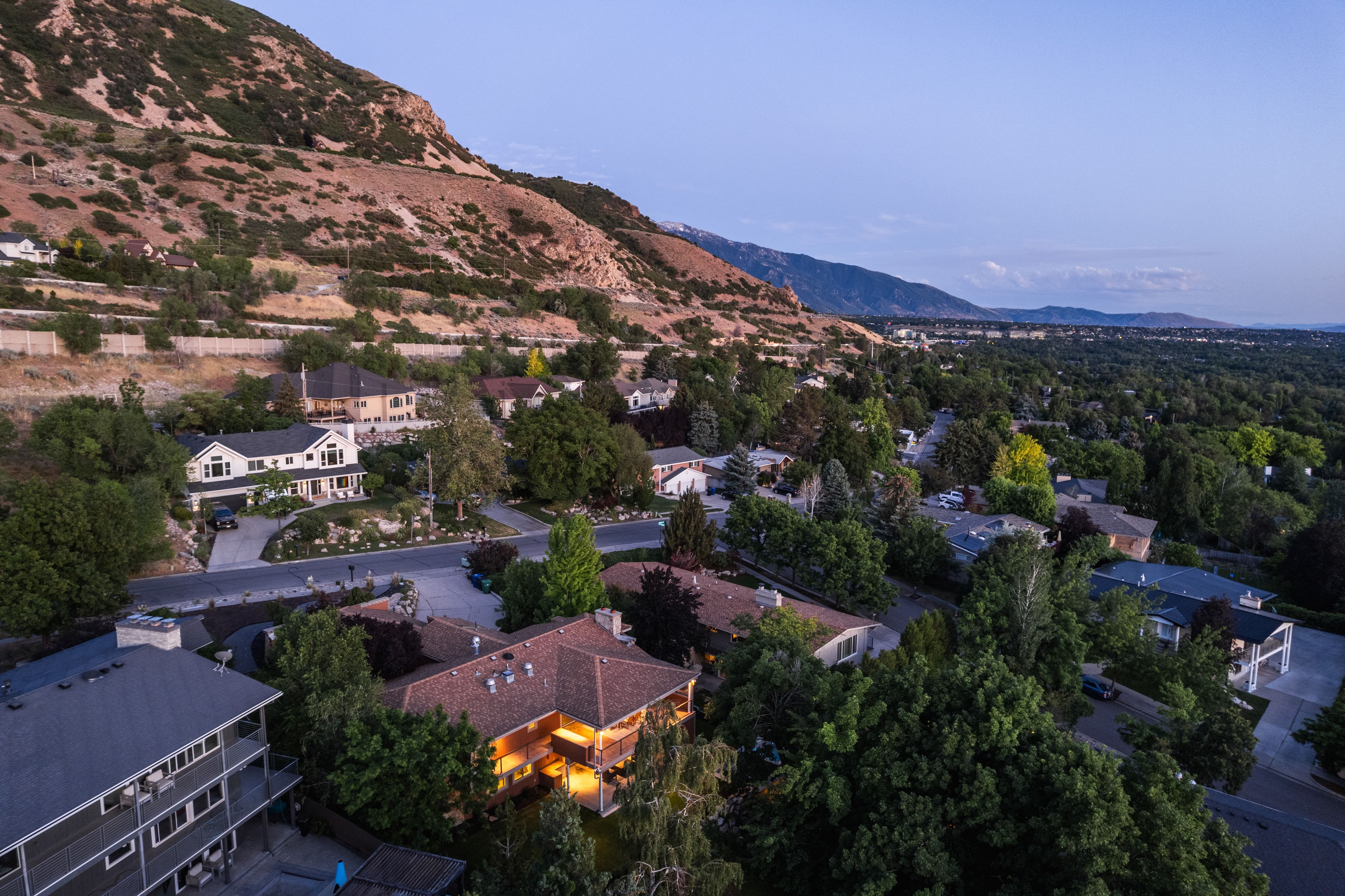 Residential neighborhood with varied architectural styles, mature trees, and mountainous topography