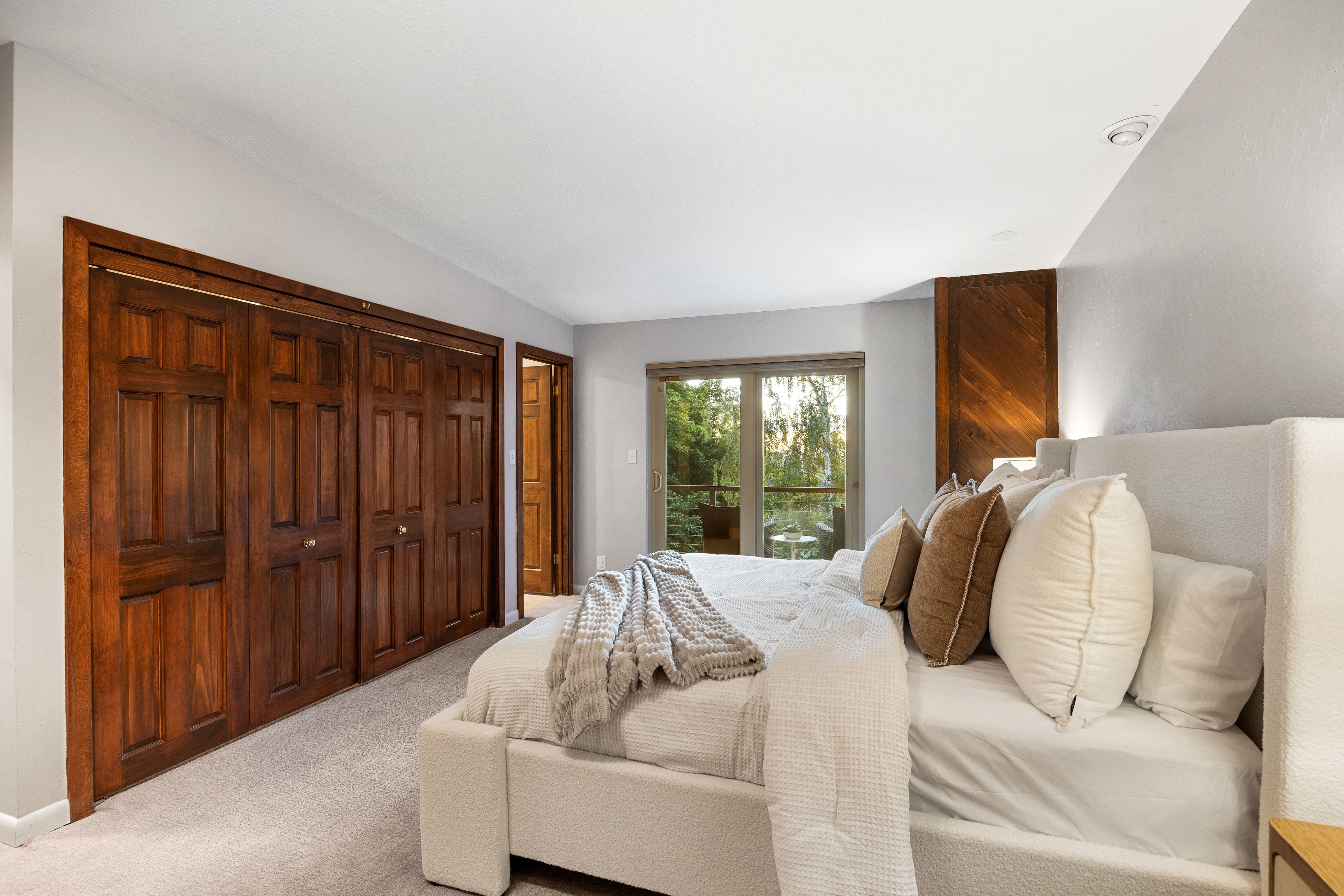 Bedroom featuring wood-finish bi-fold closet doors, light gray wall paint, recessed ceiling lighting, and a wood-paneled accent wall