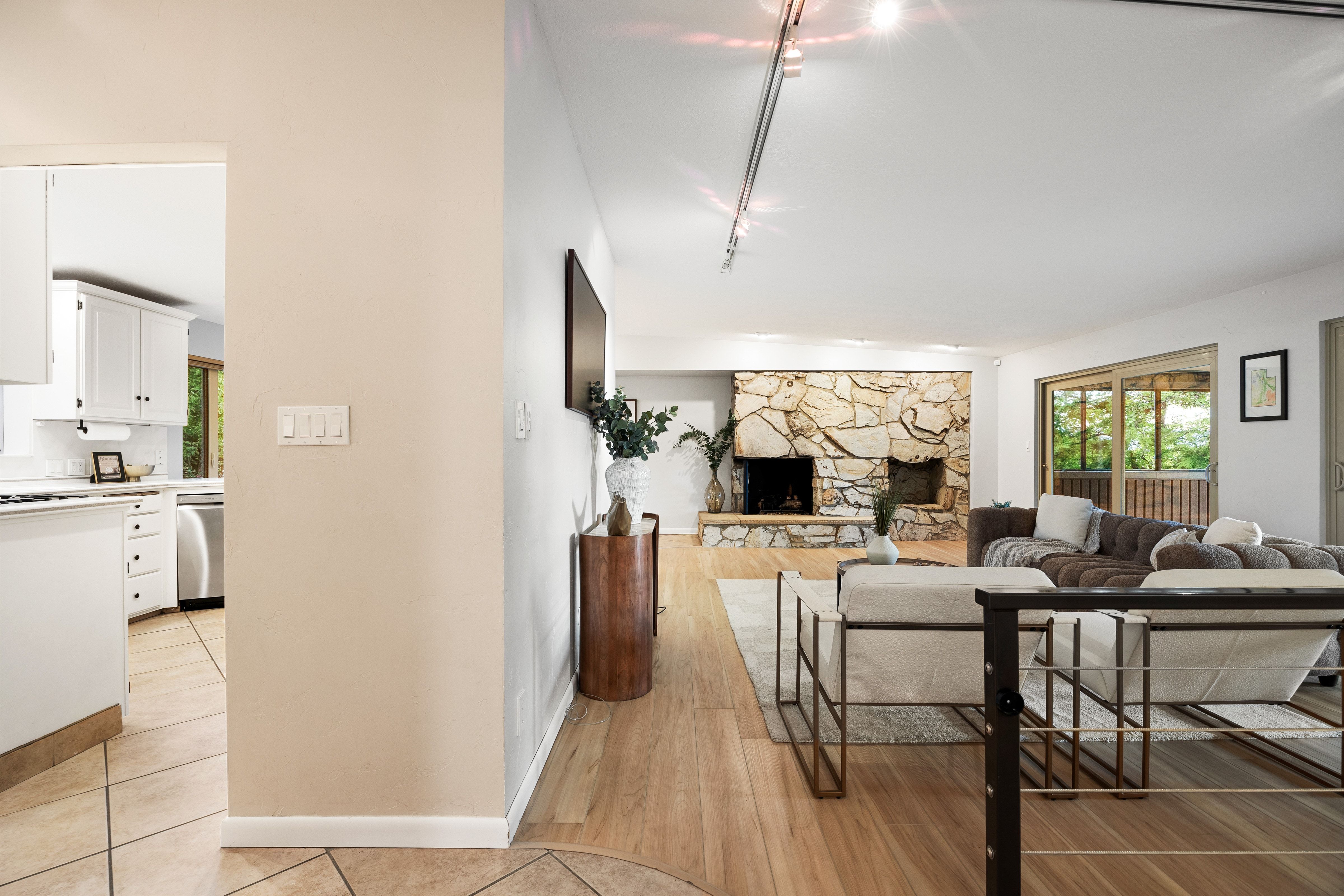 Open concept living space featuring wood-finish flooring, a stone fireplace, and sliding glass doors