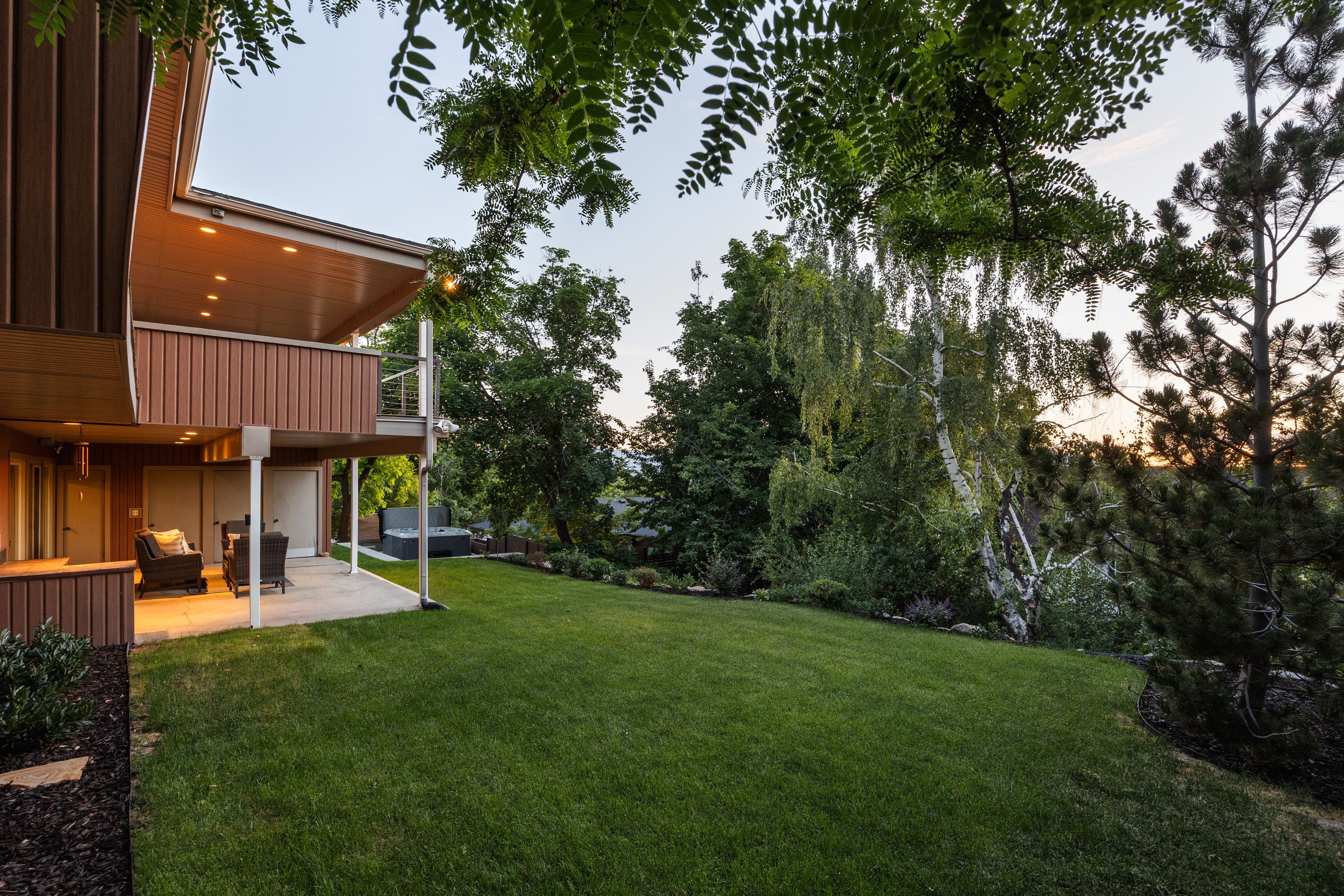 Expansive backyard featuring a manicured lawn, established landscaping, and mature trees