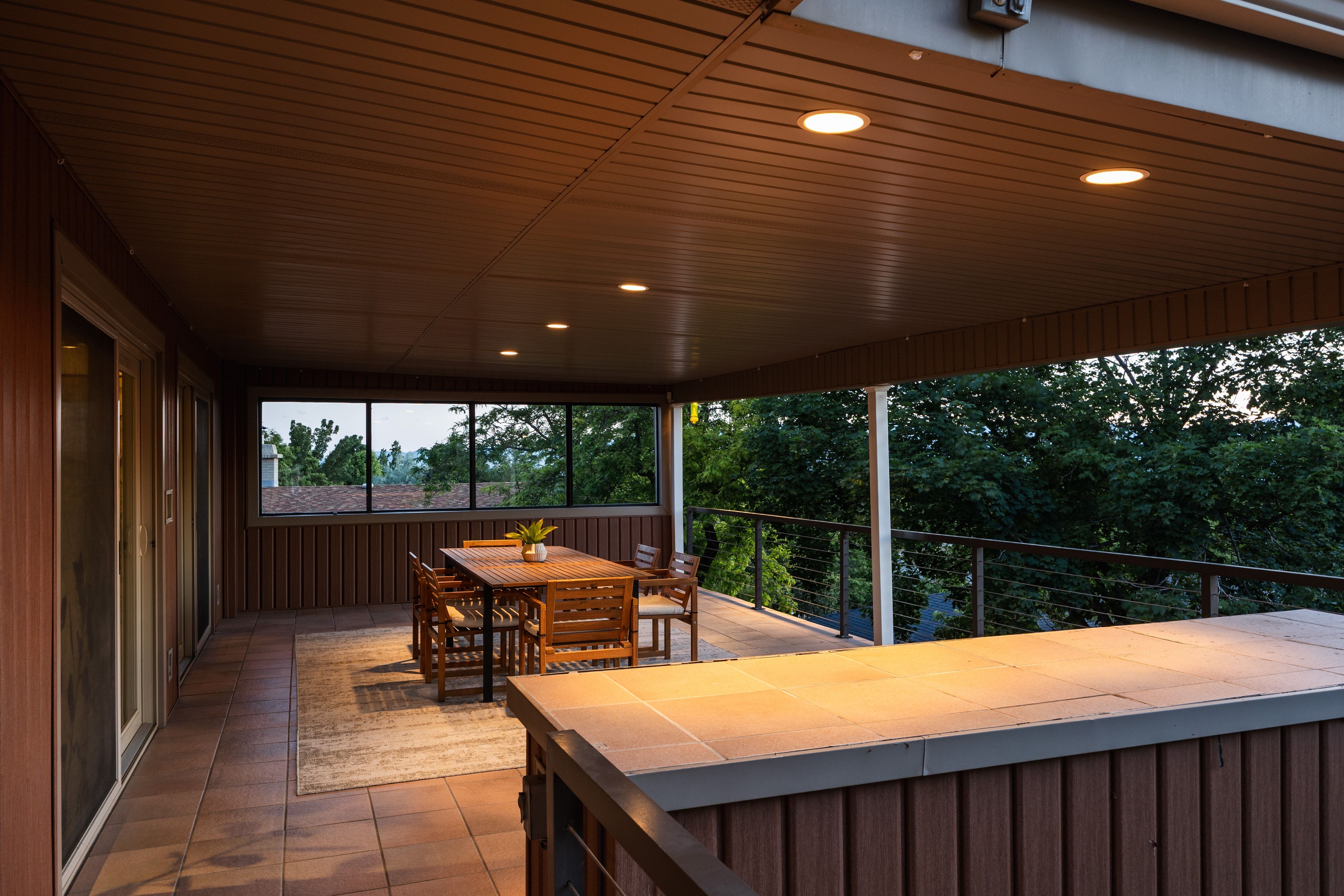 Spacious covered outdoor living area featuring wood-finish siding, recessed lighting, and tile flooring
