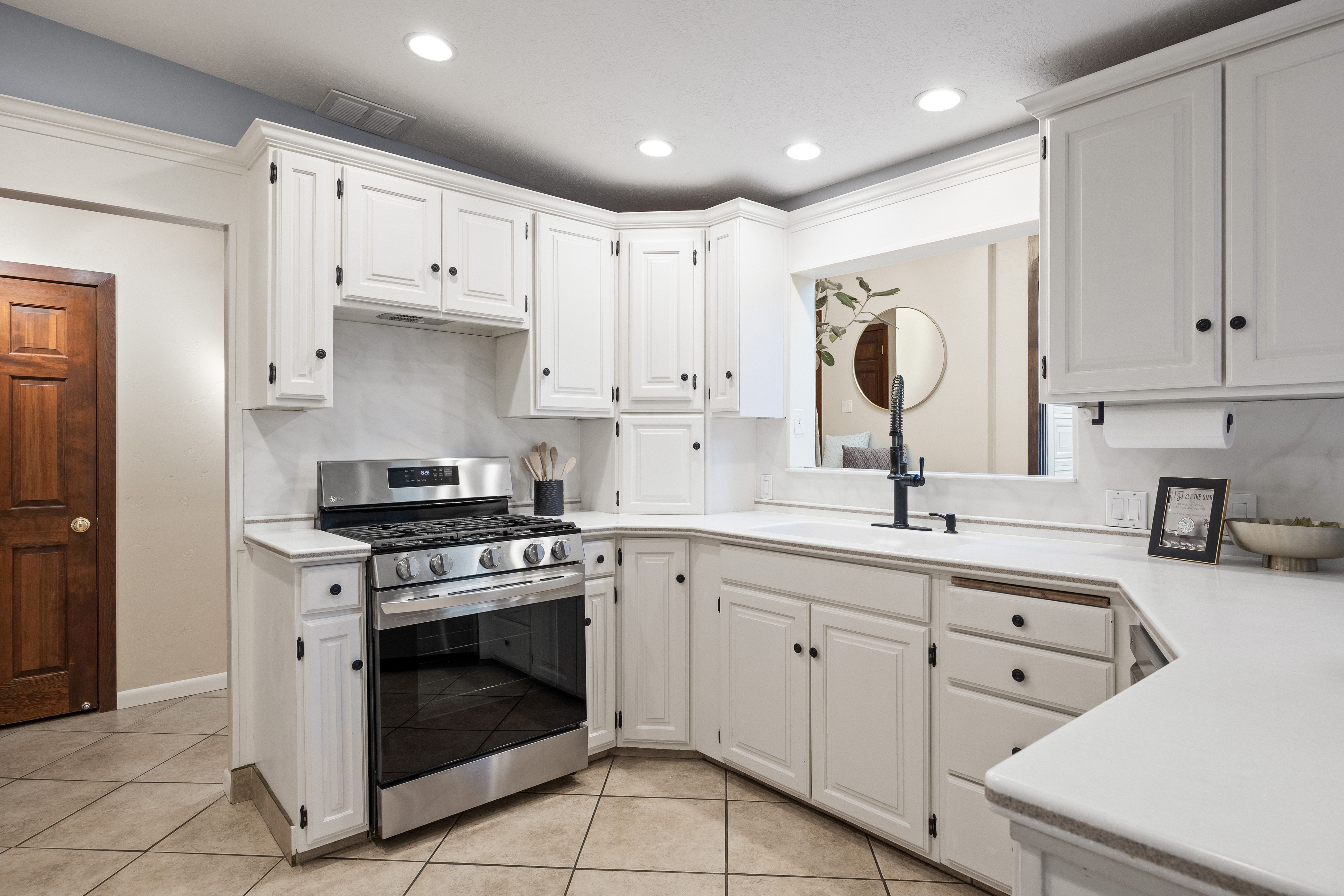 Updated kitchen featuring white shaker-style cabinetry with black hardware, a stainless steel range, and a single-basin sink with a matte black faucet