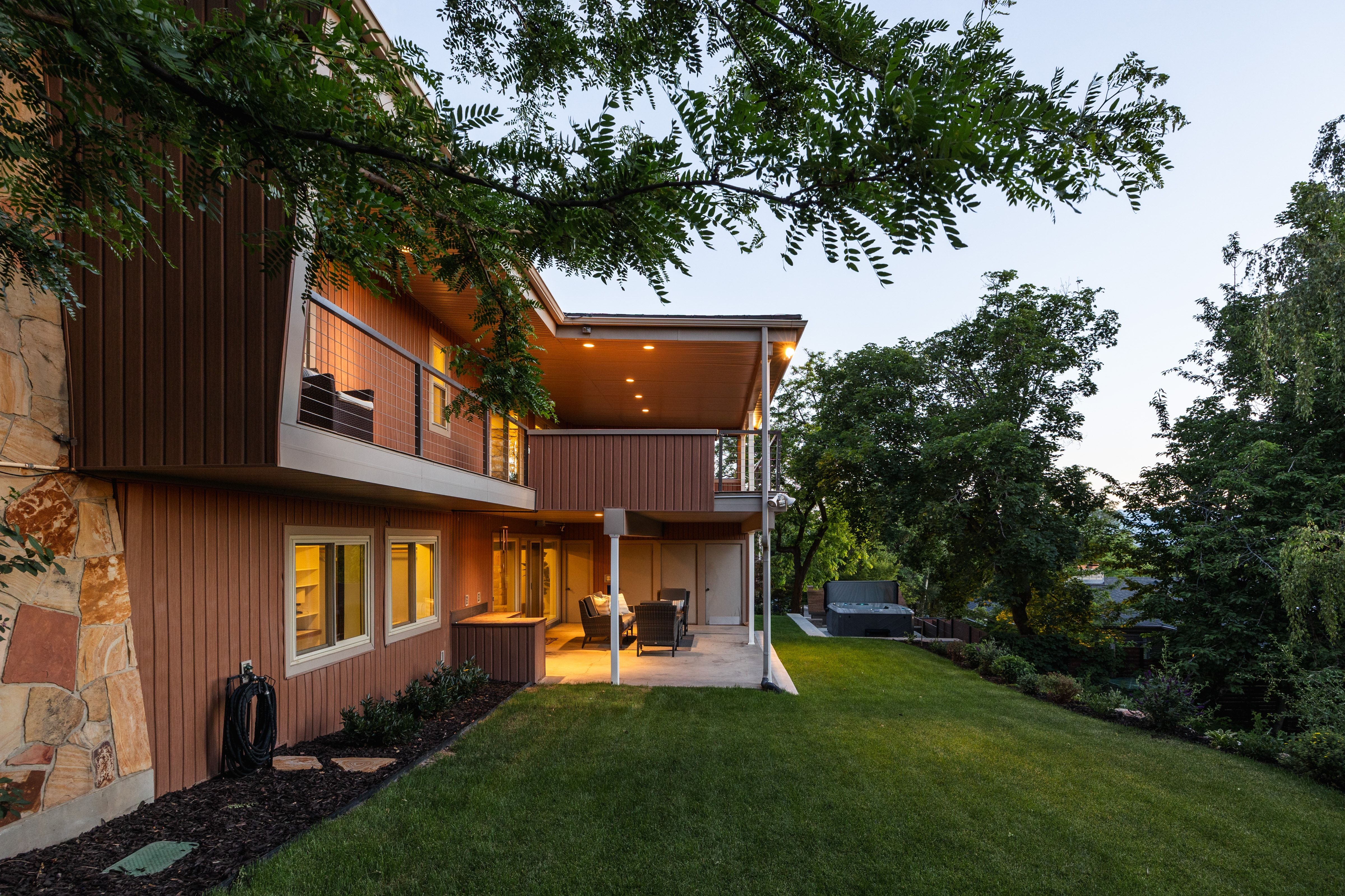 Multi-level exterior featuring wood-finish siding, stone accents, and a spacious lawn
