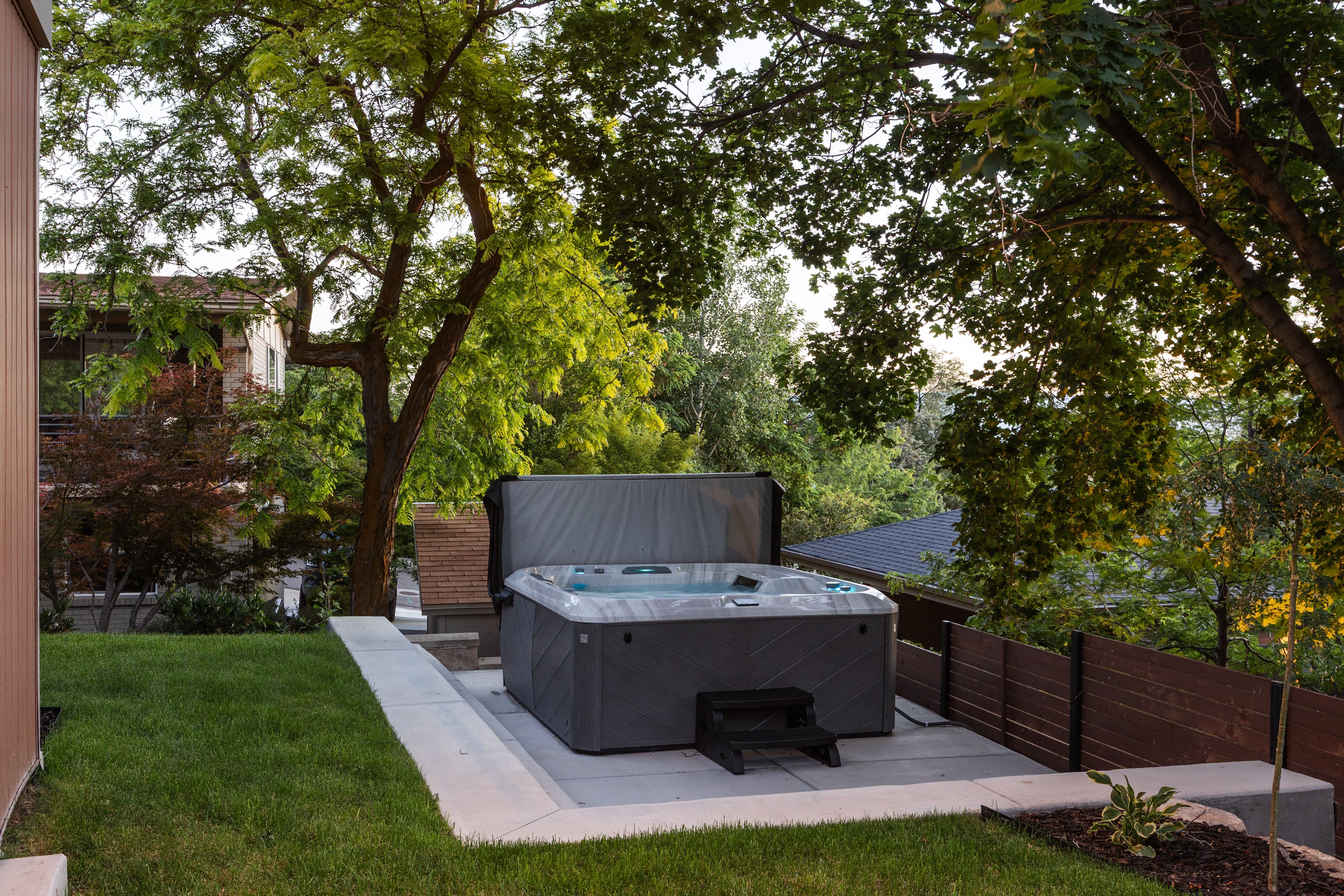 Outdoor spa with a grey textured finish, set on a light-toned concrete patio