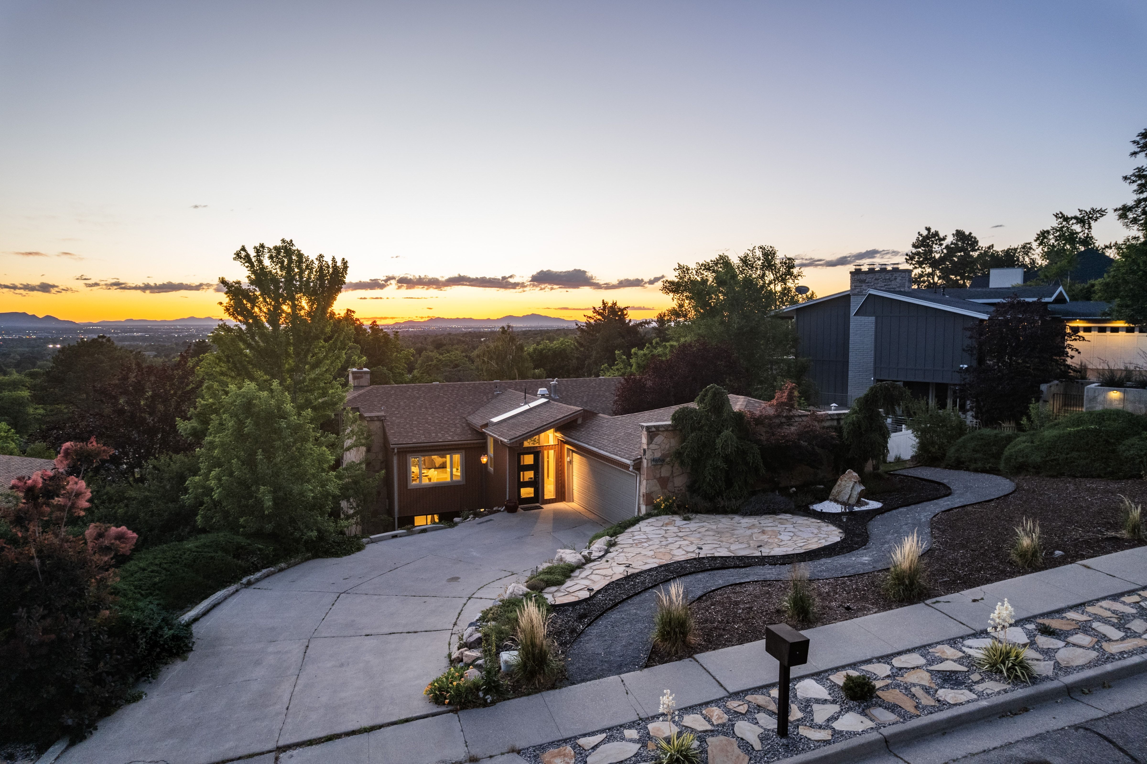 Contemporary residence featuring a prominent front entrance with vertical window accents, a paved driveway, and an attached garage