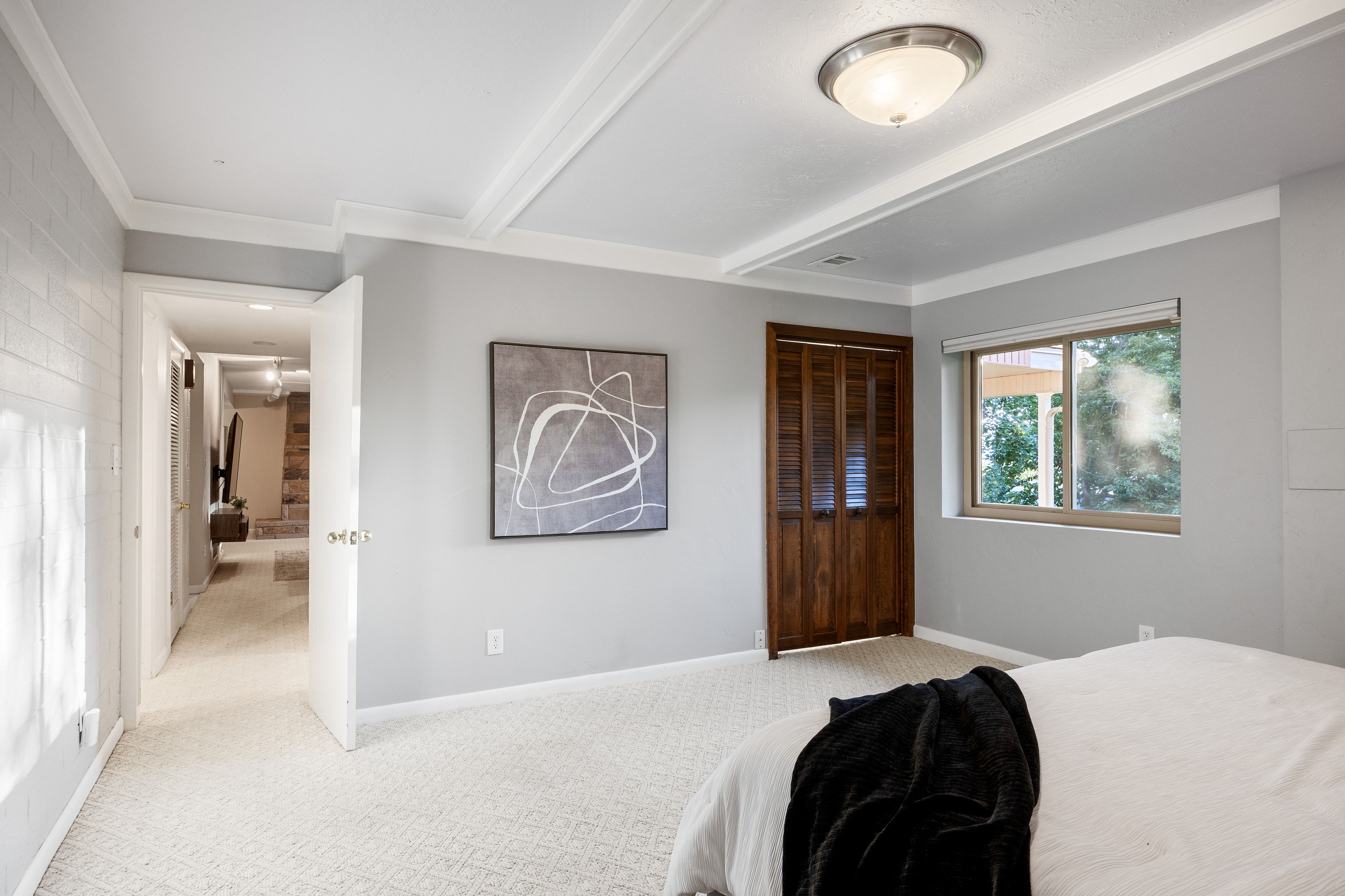 Spacious room featuring light gray walls, white crown molding, and patterned carpeting