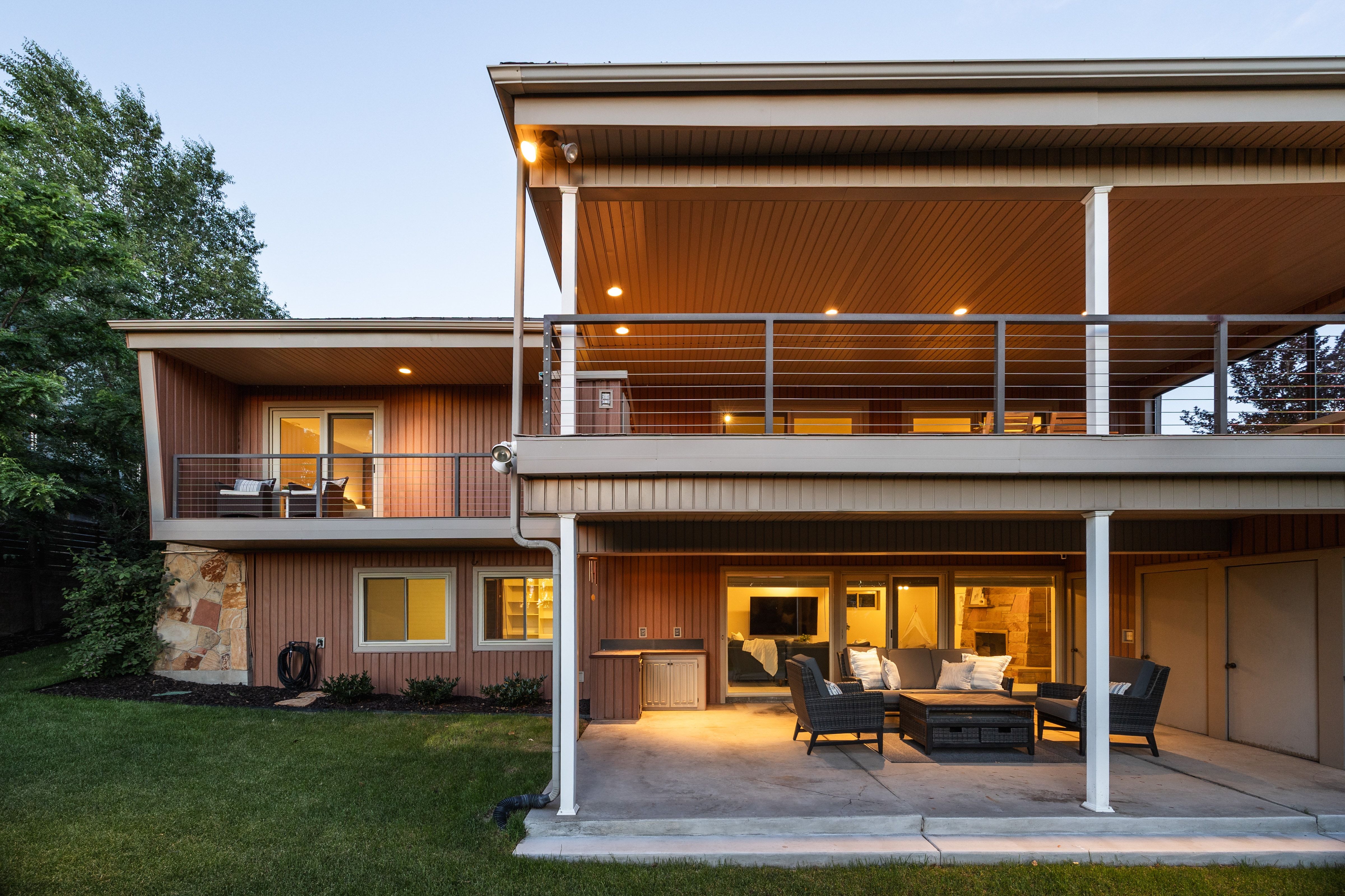 Multi-level exterior featuring wood panel siding, stone accents, and a manicured lawn