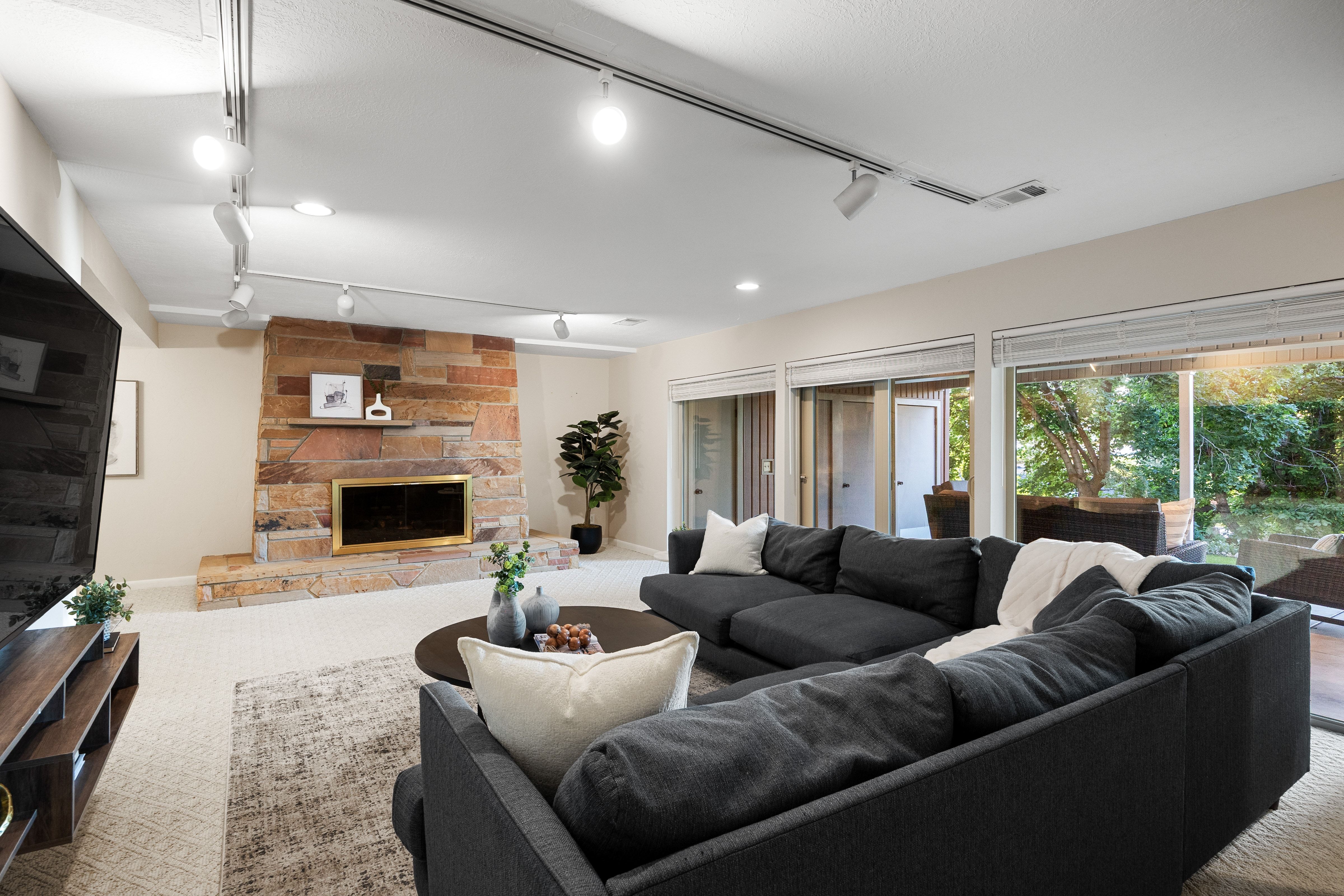 Living area featuring a stone fireplace with a brass-trimmed firebox