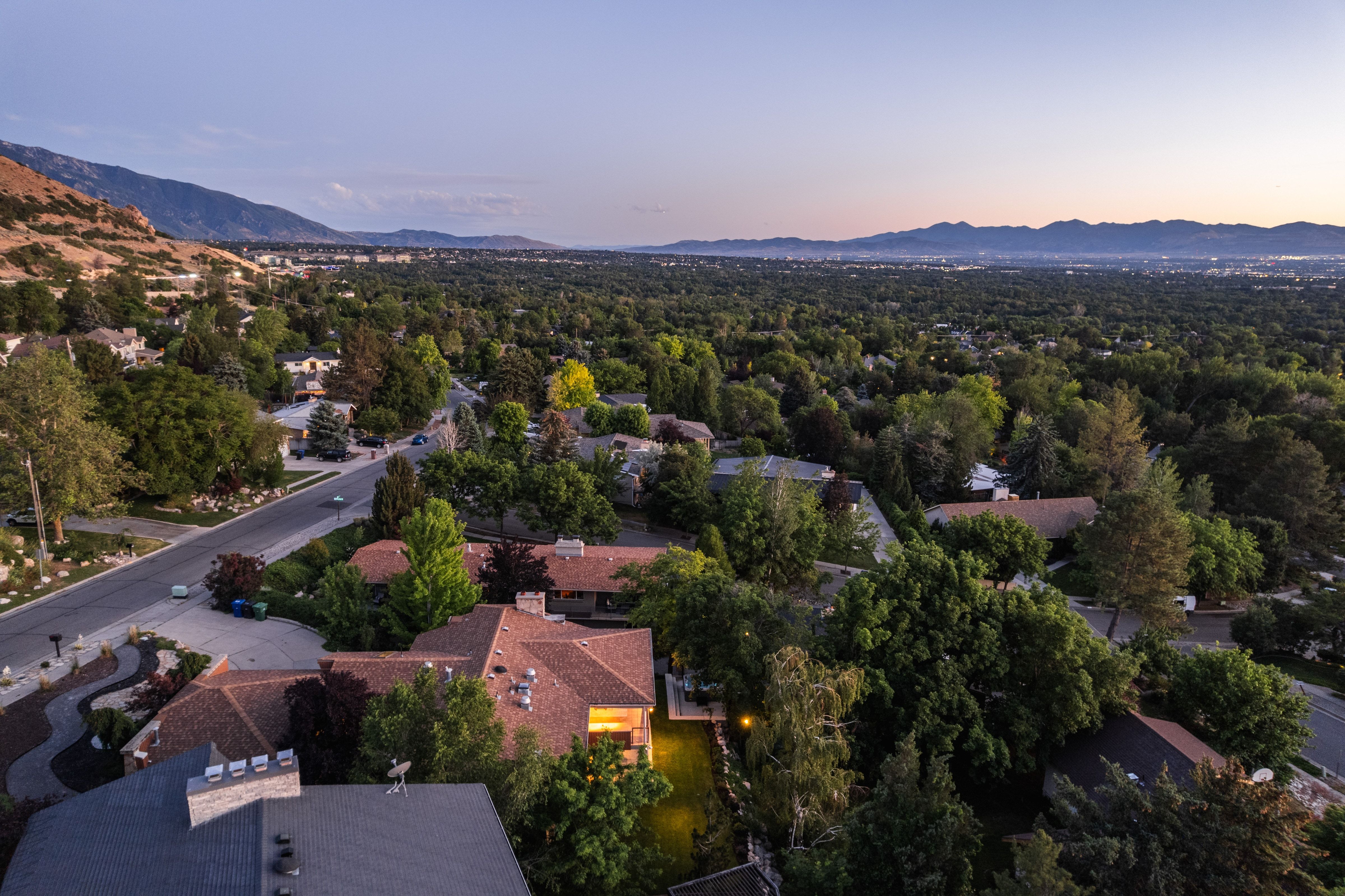 Expansive residential area featuring a prominent paved street, mature trees, and a mountain backdrop