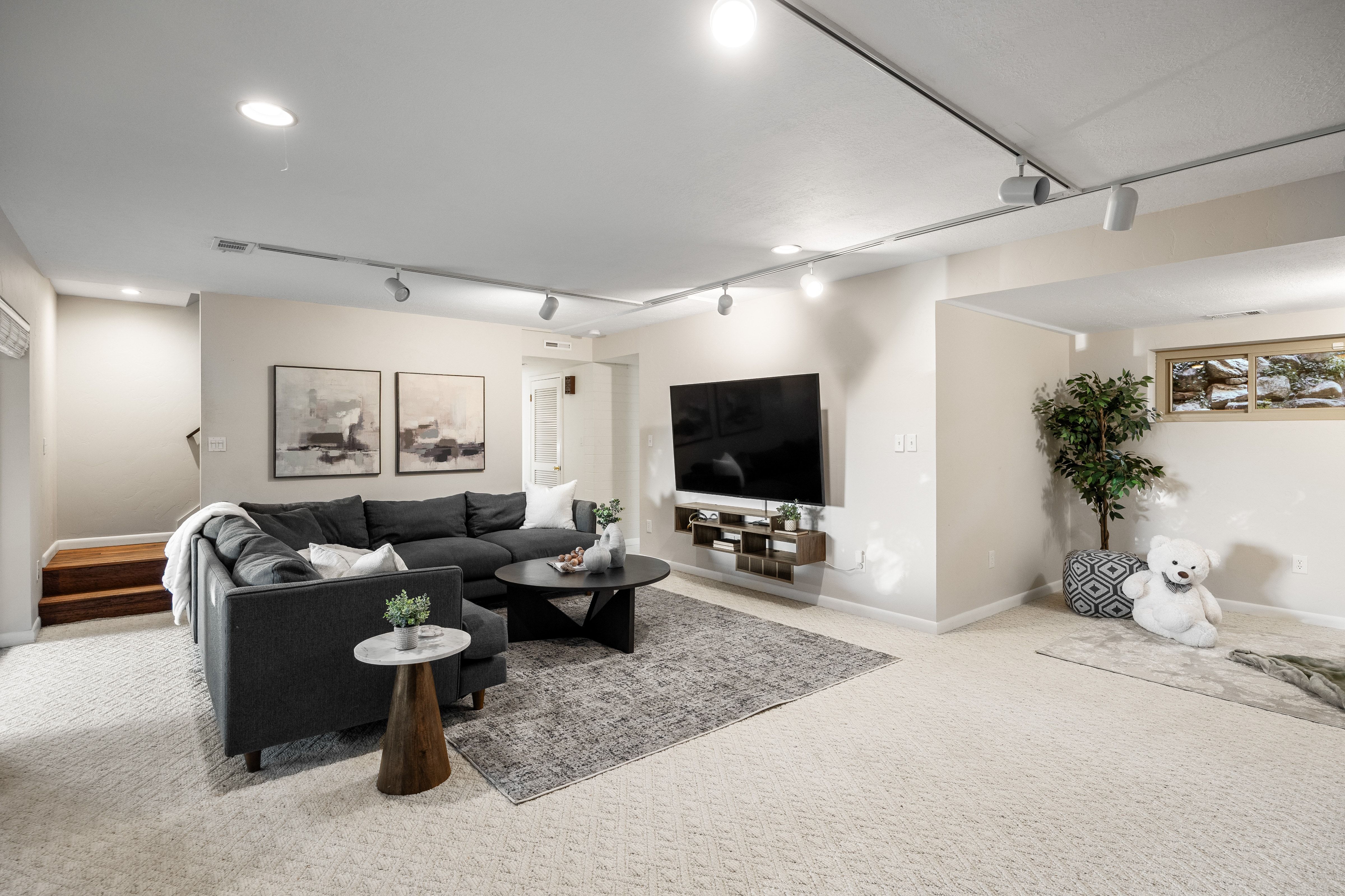 Spacious recreation room featuring patterned carpeting, recessed lighting, track lighting, and a built-in window with wood trim