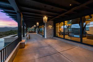 Expansive covered patio featuring a concrete surface, black beam pergola, and a stone wall accent