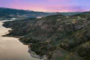 Expansive mountain landscape featuring a large body of water, rolling hills, and scattered residential properties