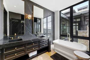Luxurious bathroom featuring a freestanding soaking tub, expansive black-framed windows, and a dual vanity with integrated sinks