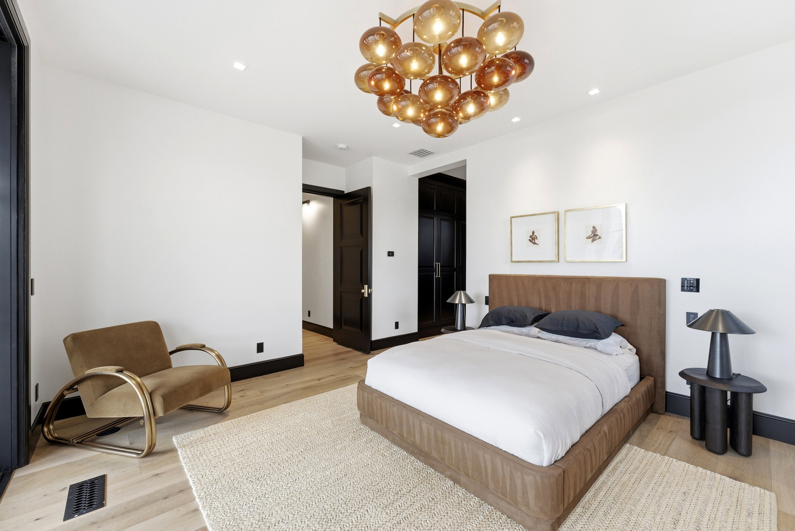 Spacious room featuring wood-finish flooring, white walls, and a large multi-globe chandelier