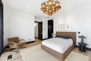 Spacious room featuring wood-finish flooring, white walls, and a large multi-globe chandelier