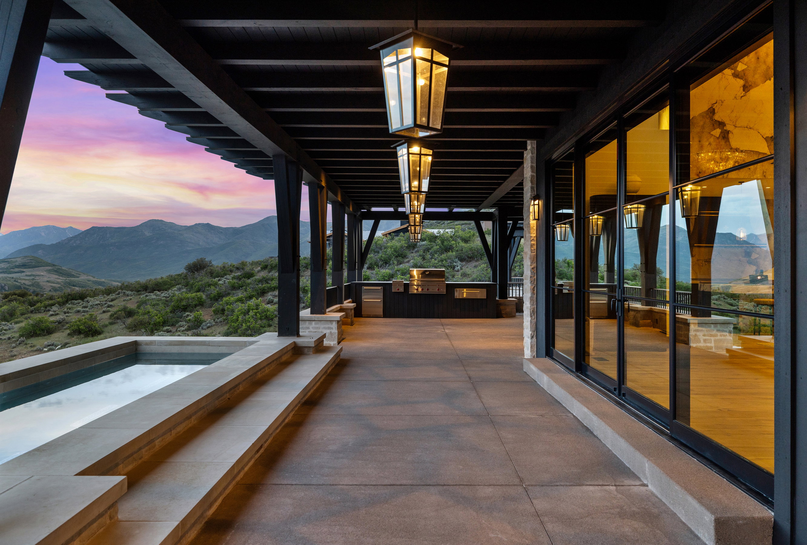 Expansive outdoor patio with a built-in spa, pergola, and an outdoor kitchen featuring a grill and cabinetry